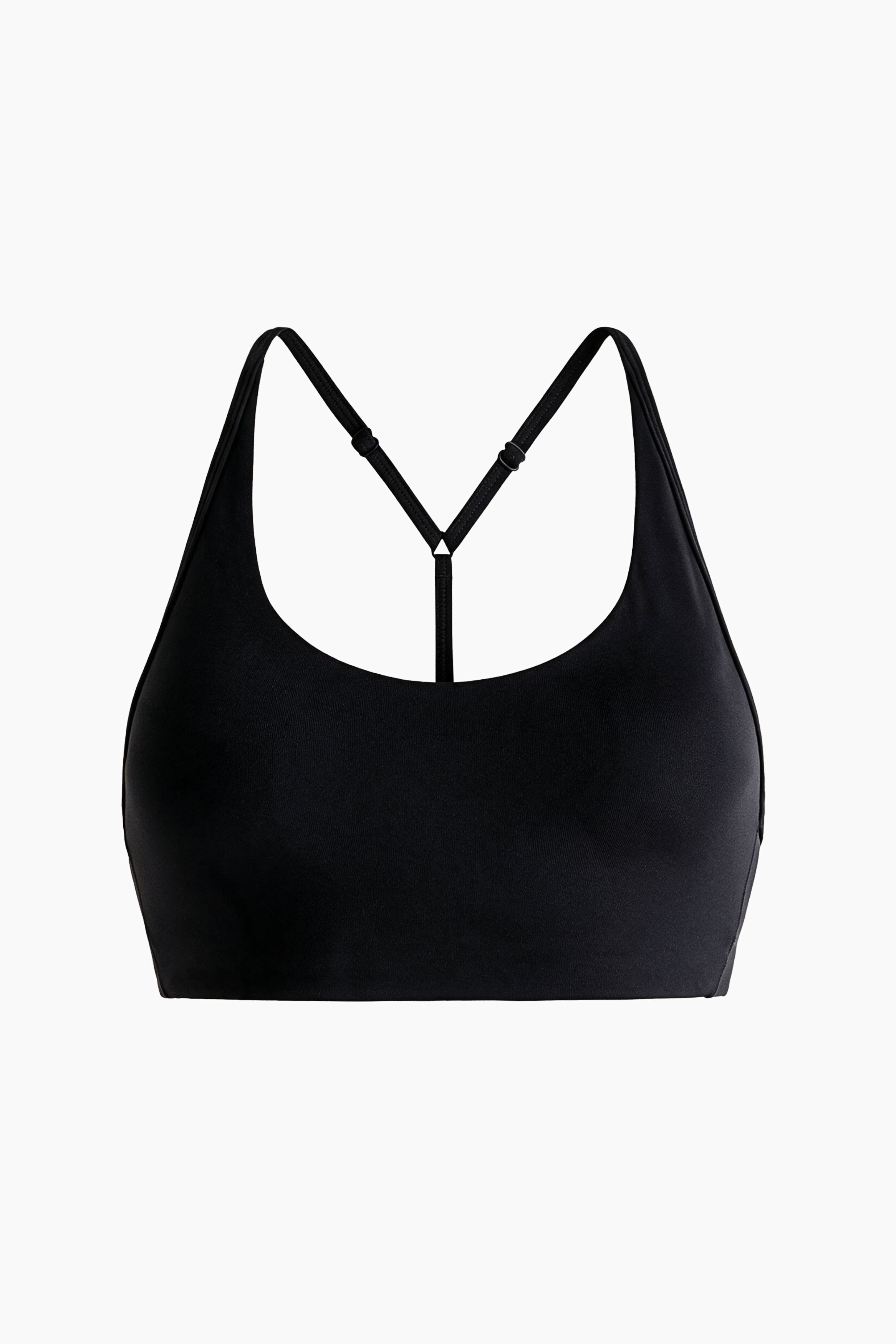 Il modello indossa un reggiseno sportivo nero con scollo rotondo e spalline larghe, in posa con le braccia sollevate dietro la testa. Il reggiseno sportivo Ã¨ abbinato a leggings neri a vita alta coordinati.