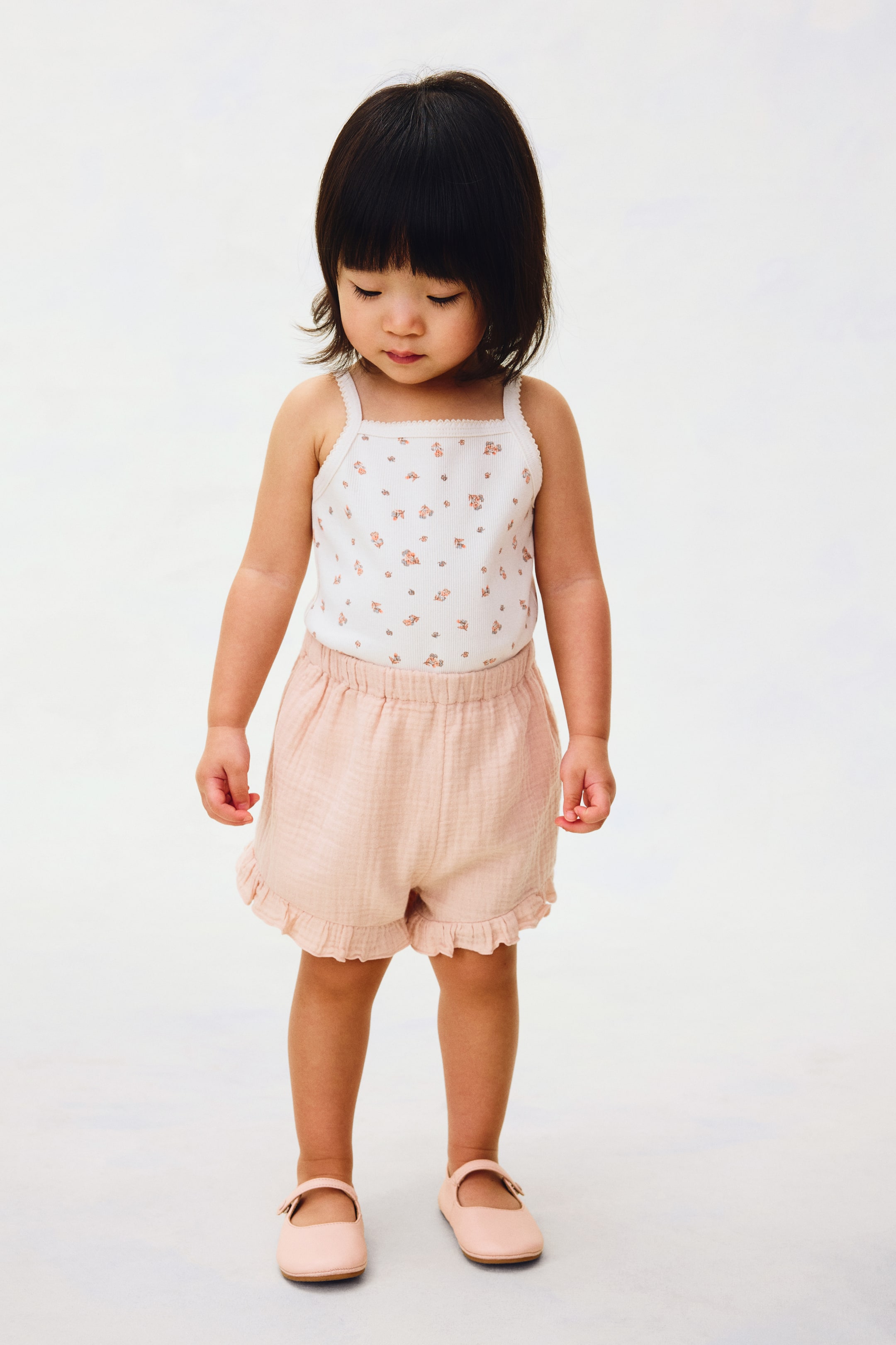 Agrandir l'image: Short en mousseline douce de couleur rose clair, confectionné en coton de haute qualité, doté d'une taille élastiquée ajustable et d'ourlets à volants, présenté de face.