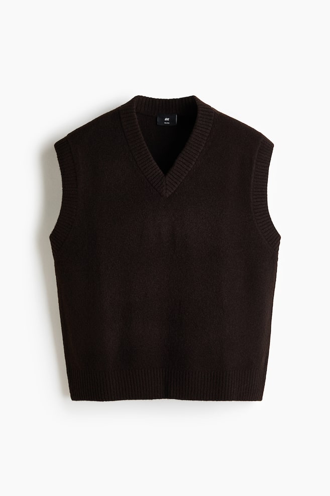 A dark brown sweater vest is featuring a V-neckline with ribbed trim, ribbed armholes, and a ribbed hem. It is displaying a softly textured knit fabric from the front. - 1