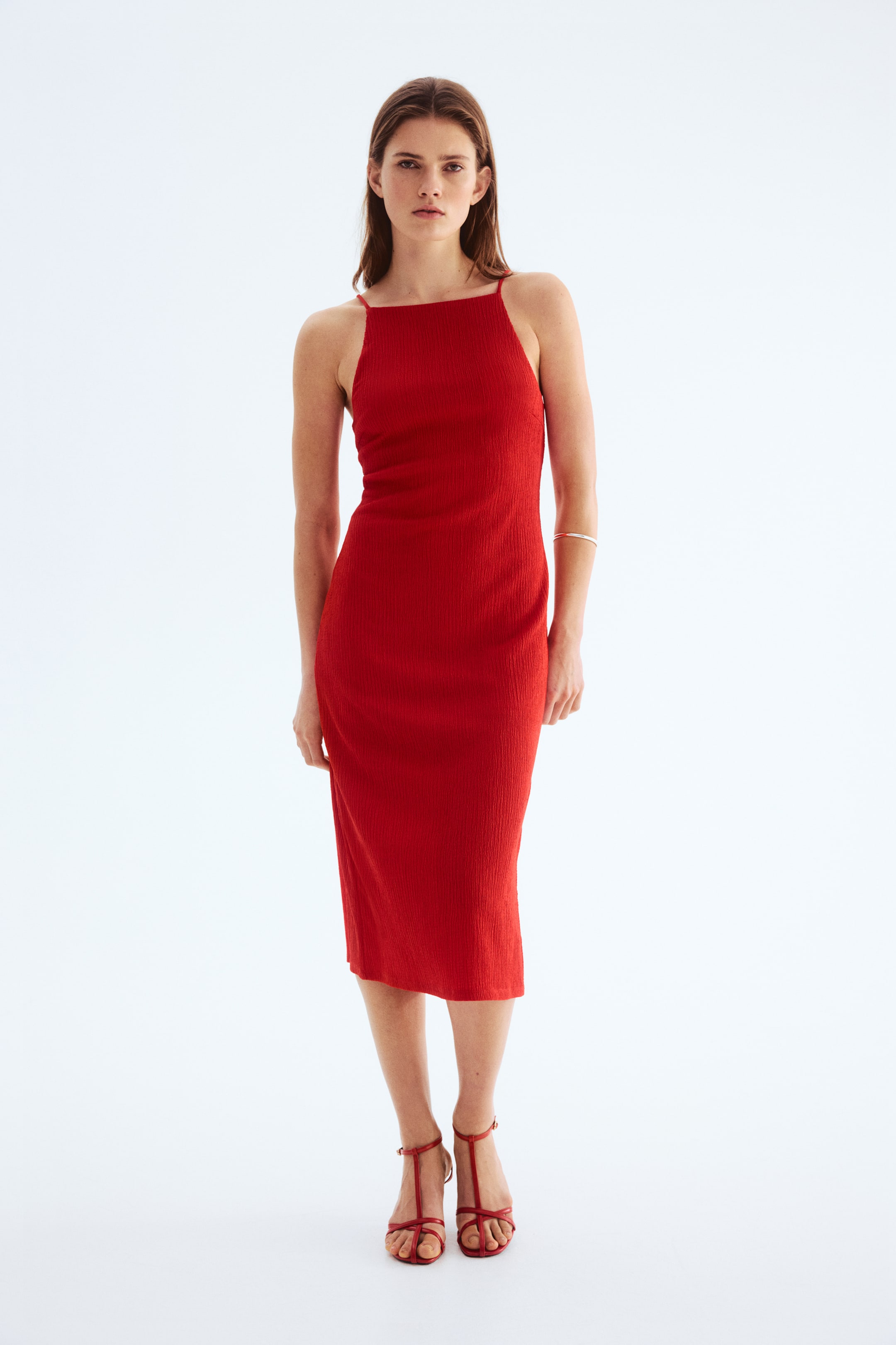 View larger image: A red ribbed knit midi dress featuring a square neckline and thin spaghetti straps, fitting snugly to the body and extending to a midi length.