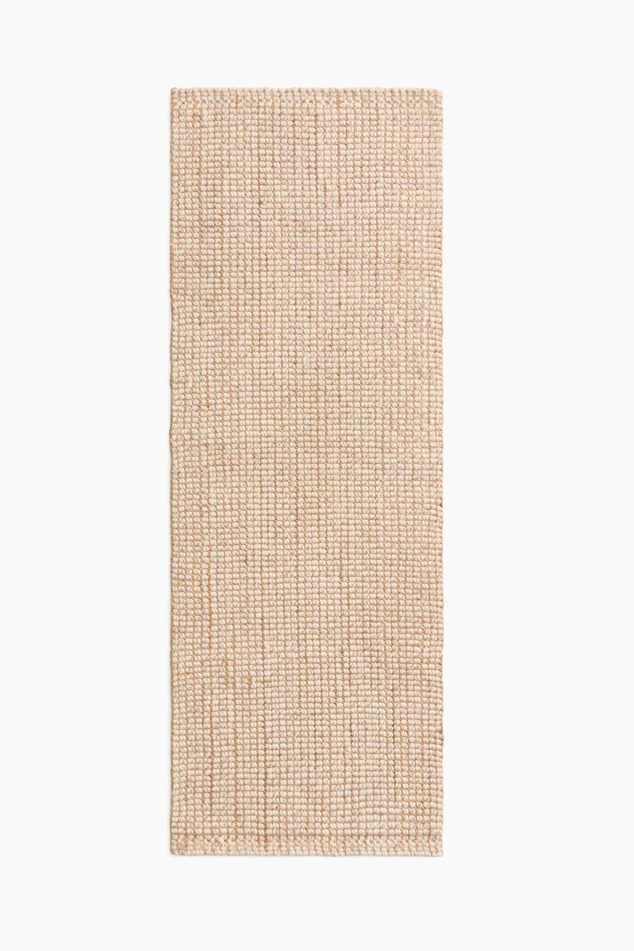 Visa större bild: En rektangulär matta ligger plant och visar en naturlig beige färg samt en tätt vävd textur med lätt ojämna kanter.