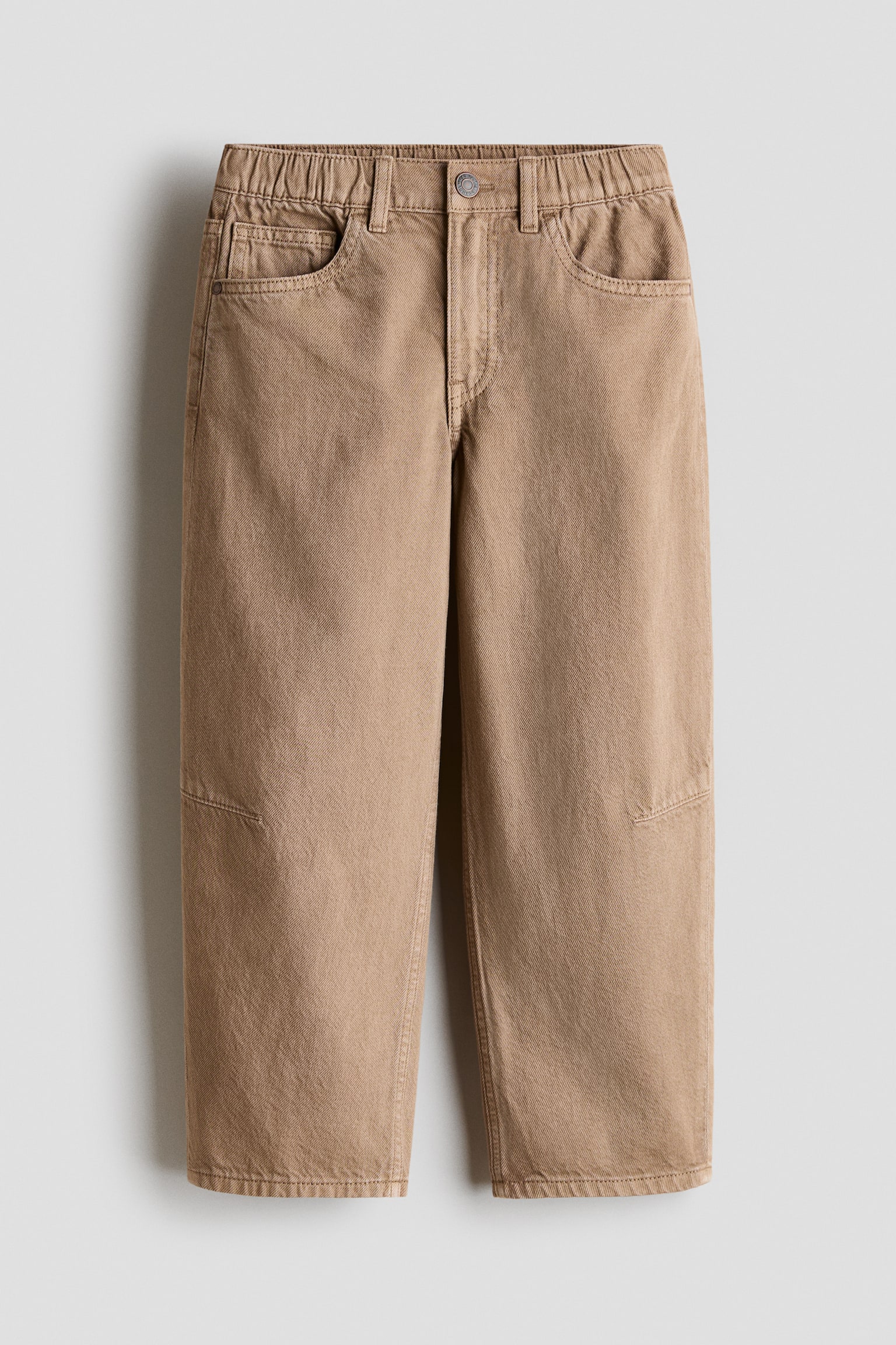 I pantaloni color cachi sono mostrati in vista frontale, con una cintura elasticizzata dotata di passanti per cintura e una chiusura con un solo bottone. Presentano anche due tasche anteriori sui fianchi e distintivi inserti rettangolari sulle ginocchia di ciascuna gamba larga. - 1