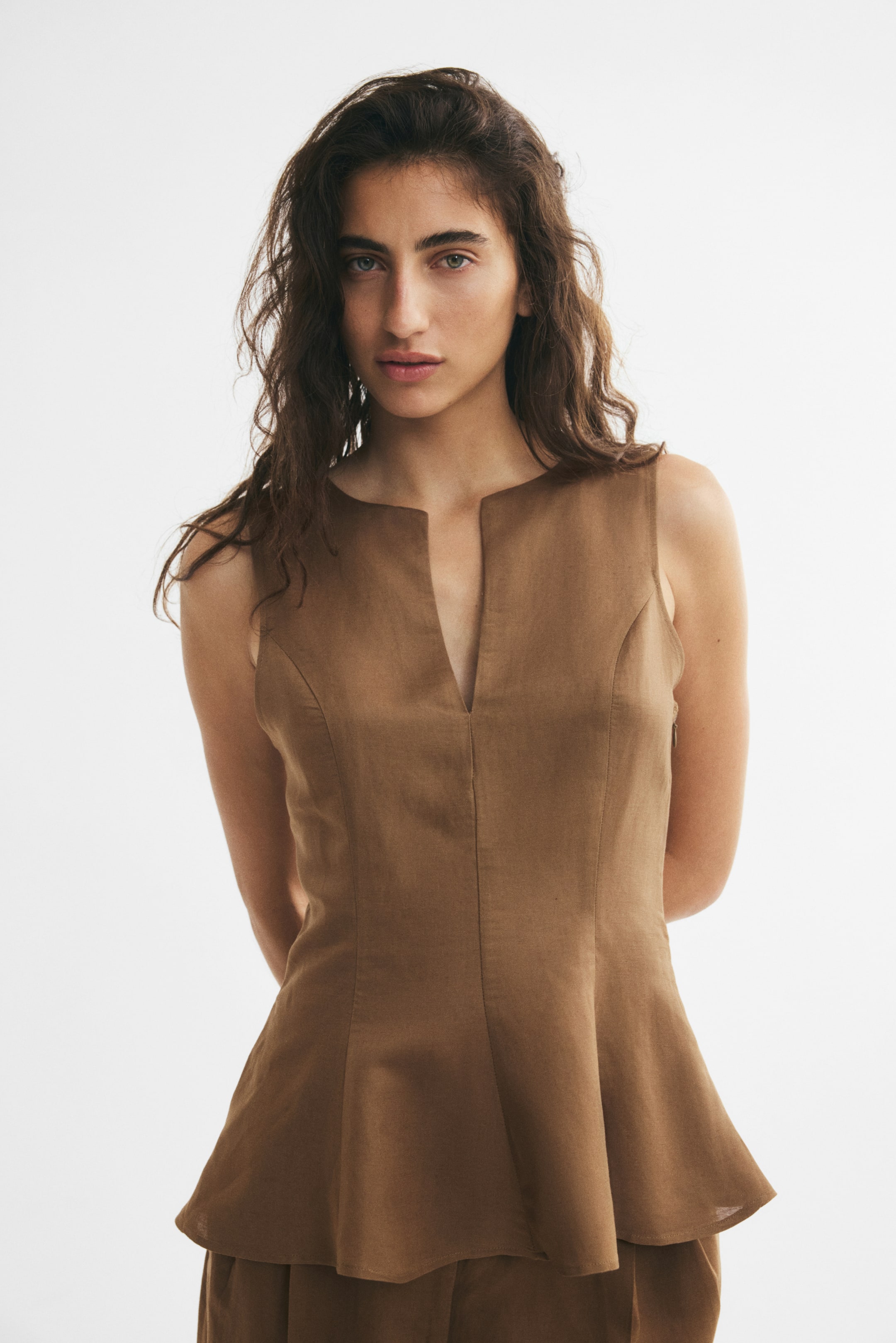 View larger image: A brown sleeveless top, featuring a V-shaped neckline, front princess seams, and a gently flared hem, is being worn by the model.