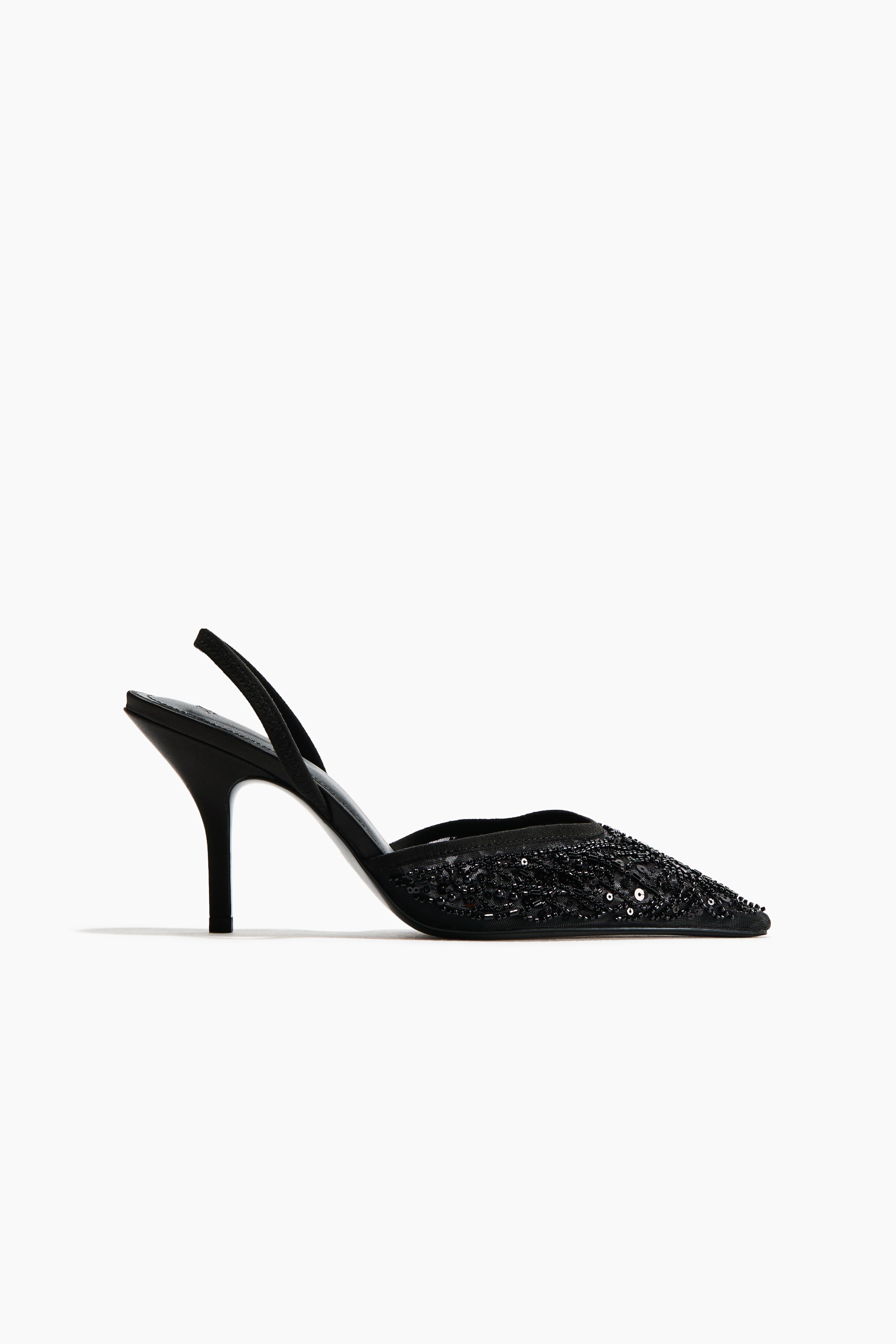 View larger image: A black slingback shoe is shown in side profile facing right, featuring a pointed toe embellished with intricate black beadwork and sequins. The shoe features a semi-sheer mesh upper, a slender stiletto heel, and a thin back strap.