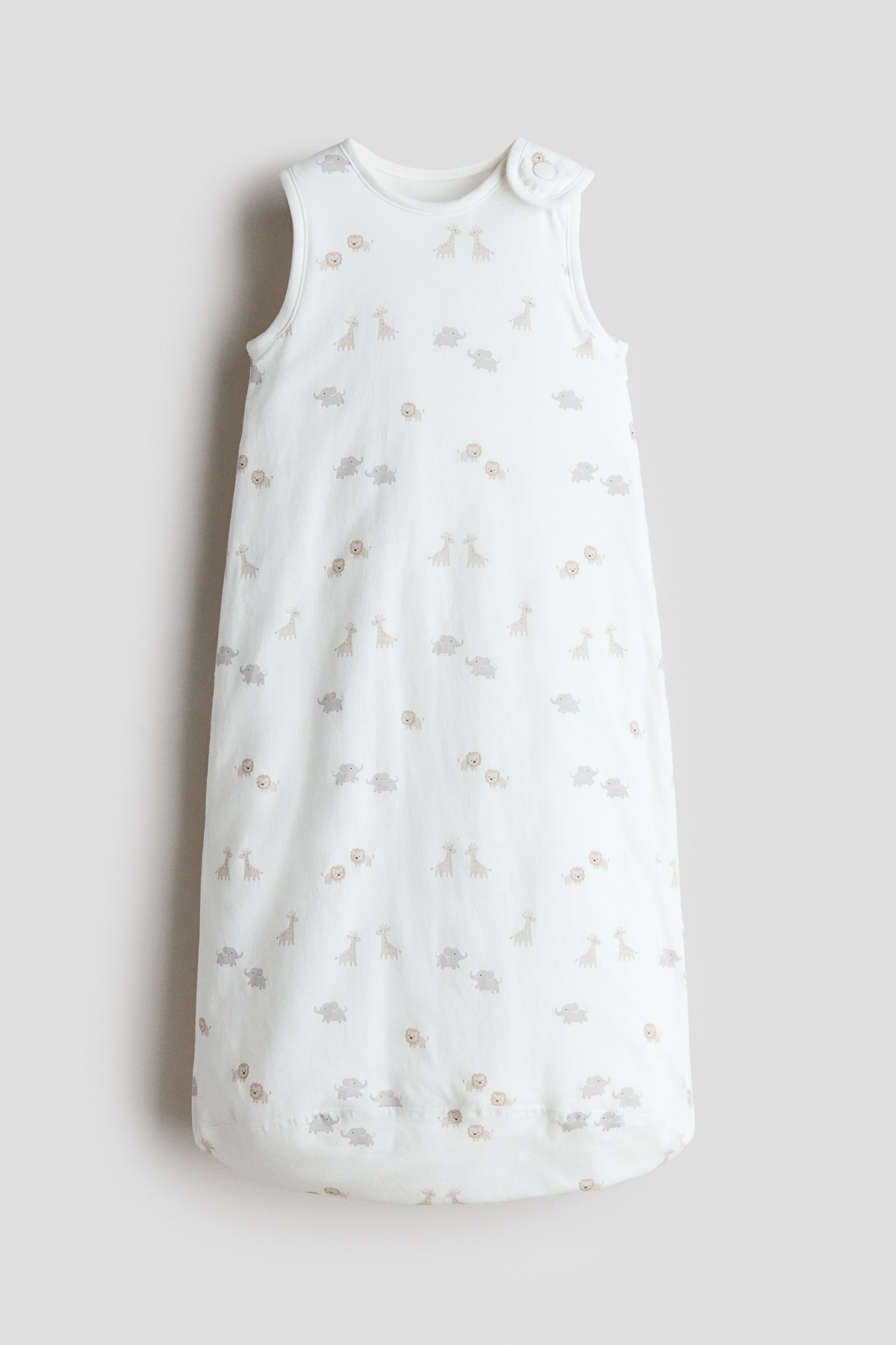 Zobacz większy obraz: Śpiworek wyściełany wykonany jest z białej bawełny jersey, ozdobiony małymi żyrafami, słoniami i lwami. Posiada okrągły dekolt, zapięcie na zatrzask na prawym ramieniu oraz zamek błyskawiczny wzdłuż jednej strony.