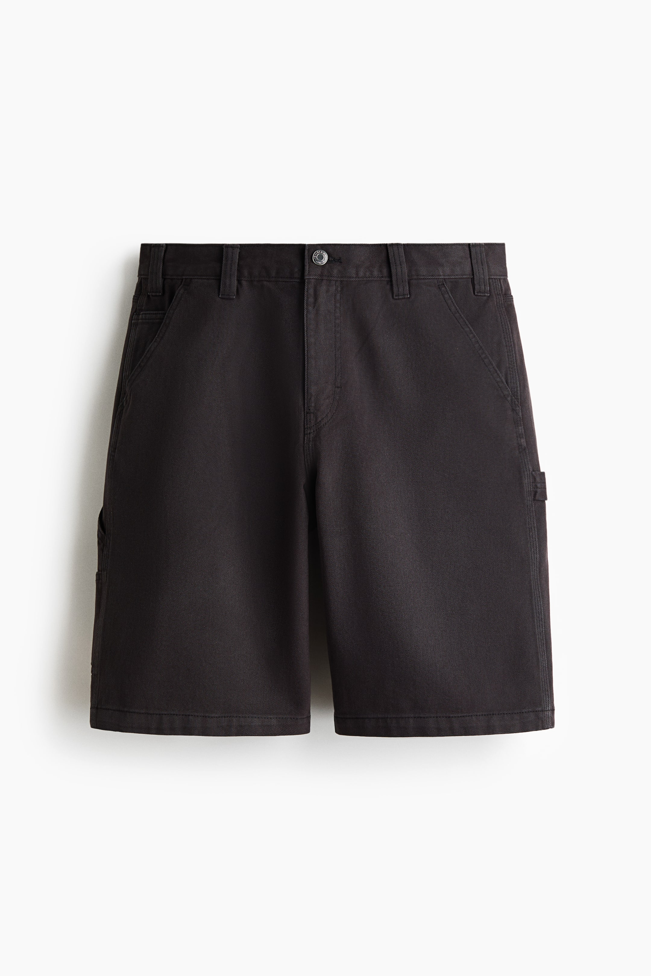 View larger image: Black carpenter shorts are shown from the front, featuring a button-and-zipper fly closure, belt loops, angled front pockets, and utility pockets on the sides.