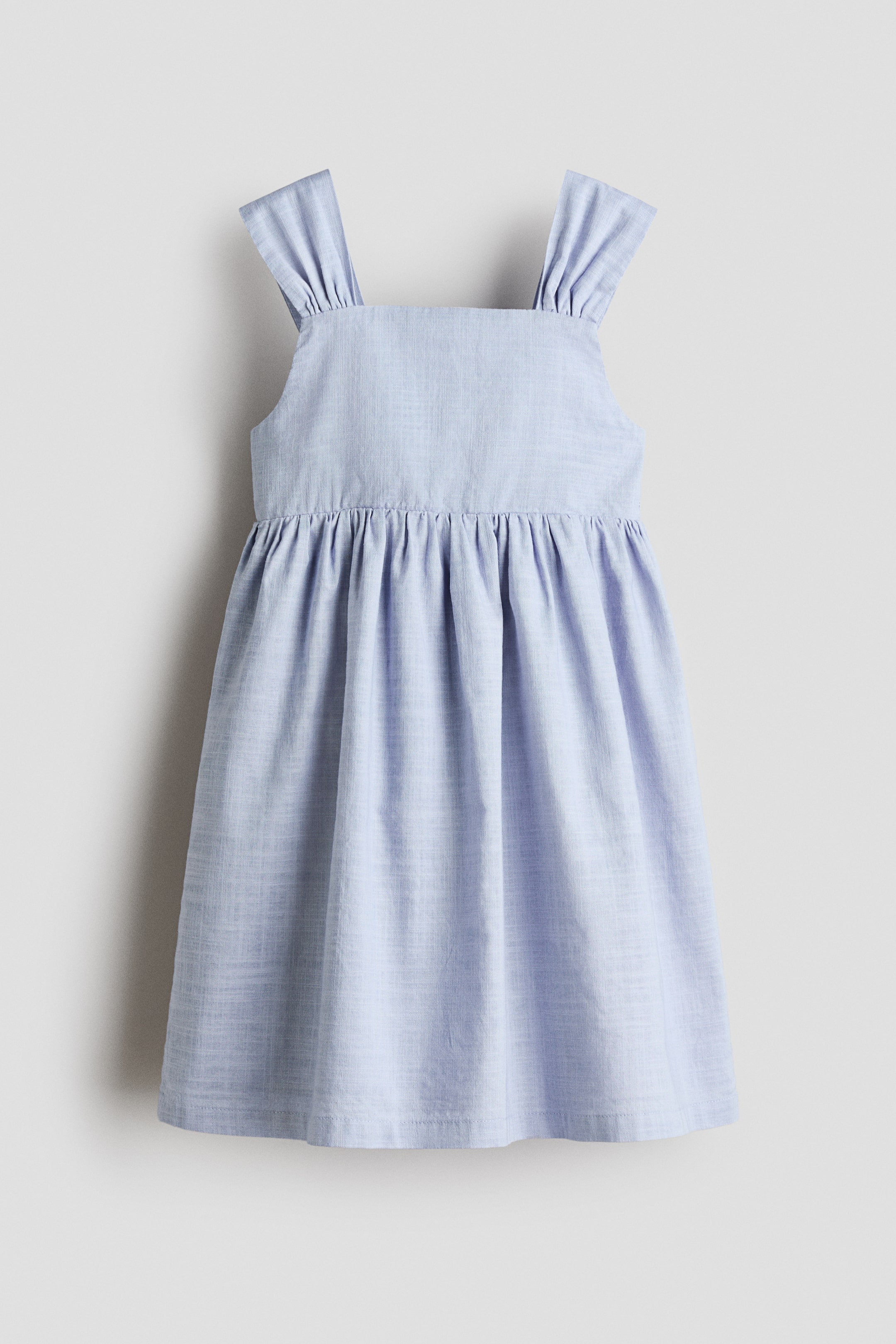 View larger image: A light blue dress featuring a square neckline and gathered shoulder straps. The bodice is plain, and a gathered waistline leads into a flared skirt made from a lightly textured fabric.
