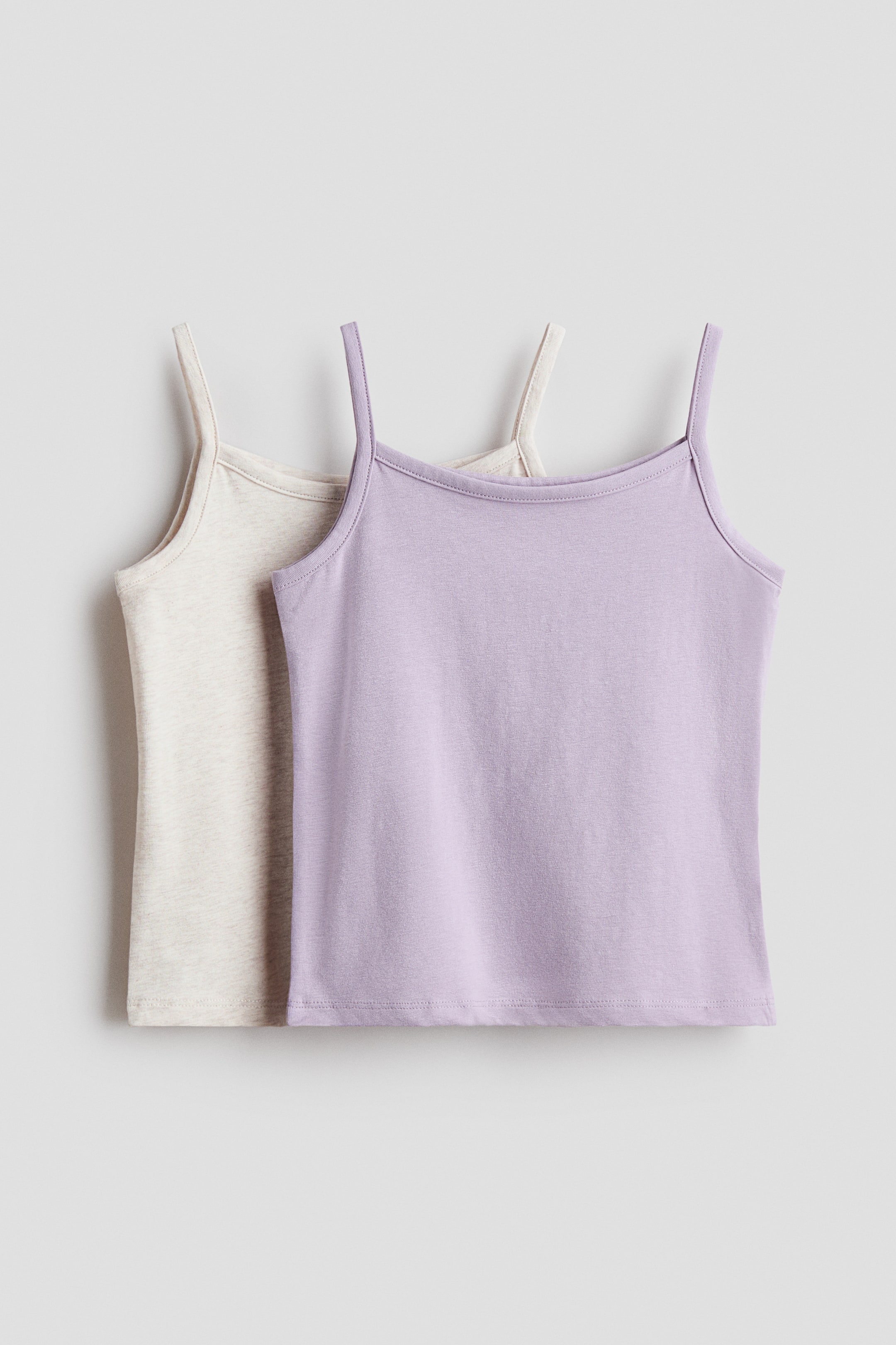 Xem ảnh lớn hơn: Hai chiếc áo thun cotton co giãn mềm mại đang được trình bày với góc nhìn phía trước, với một chiếc áo màu tím nhạt xuất hiện trước một chiếc áo màu be nhạt, cả hai đều có cổ vuông và dây đeo vai hẹp.