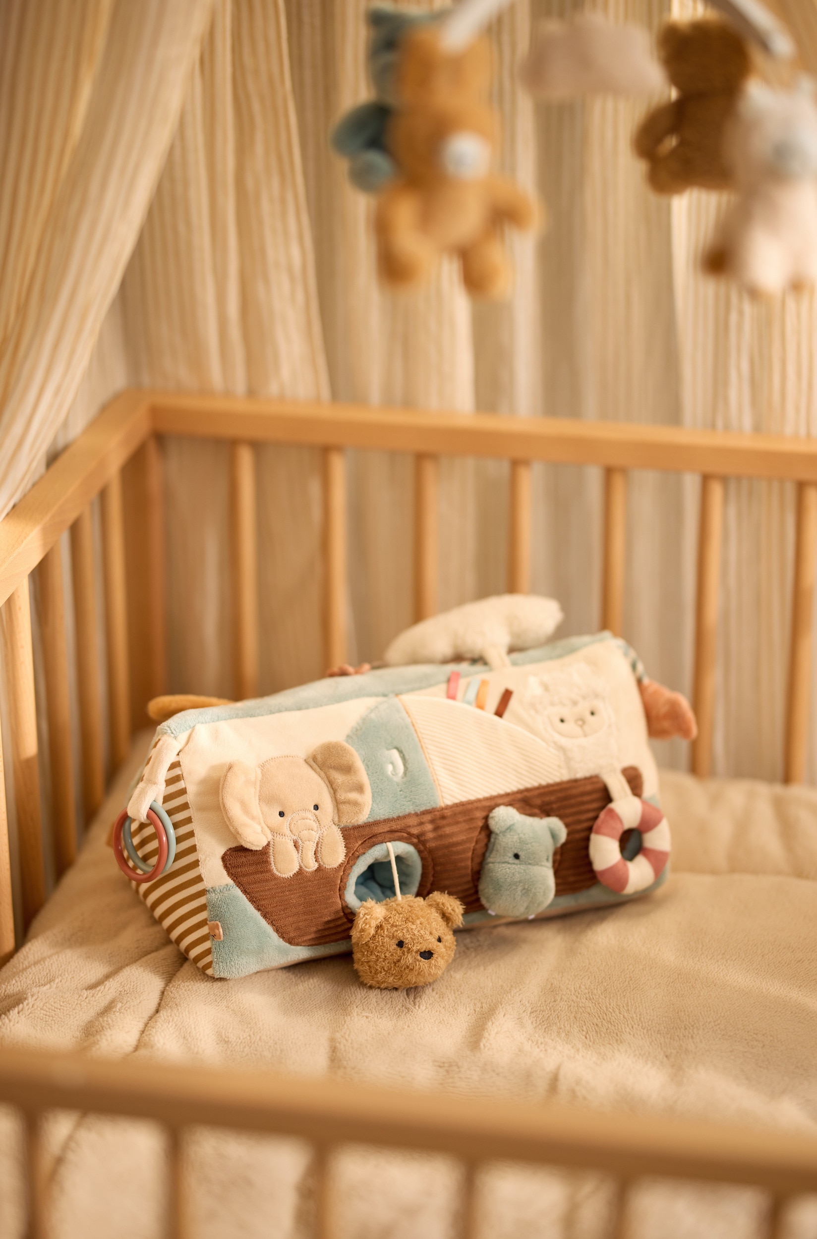Un jouet dâÃ©veil en forme de cale, doux et moelleux, est posÃ© en biais Ã  trois quarts, mettant en valeur un extÃ©rieur en sherpa bleu poudrÃ© et crÃ¨me. Le panneau avant prÃ©sente une appliquÃ© de lapin en peluche, un petit papillon et un motif de montgolfiÃ¨re avec un rabat nuage Ã  soulever rÃ©vÃ©lant un petit miroir rond.