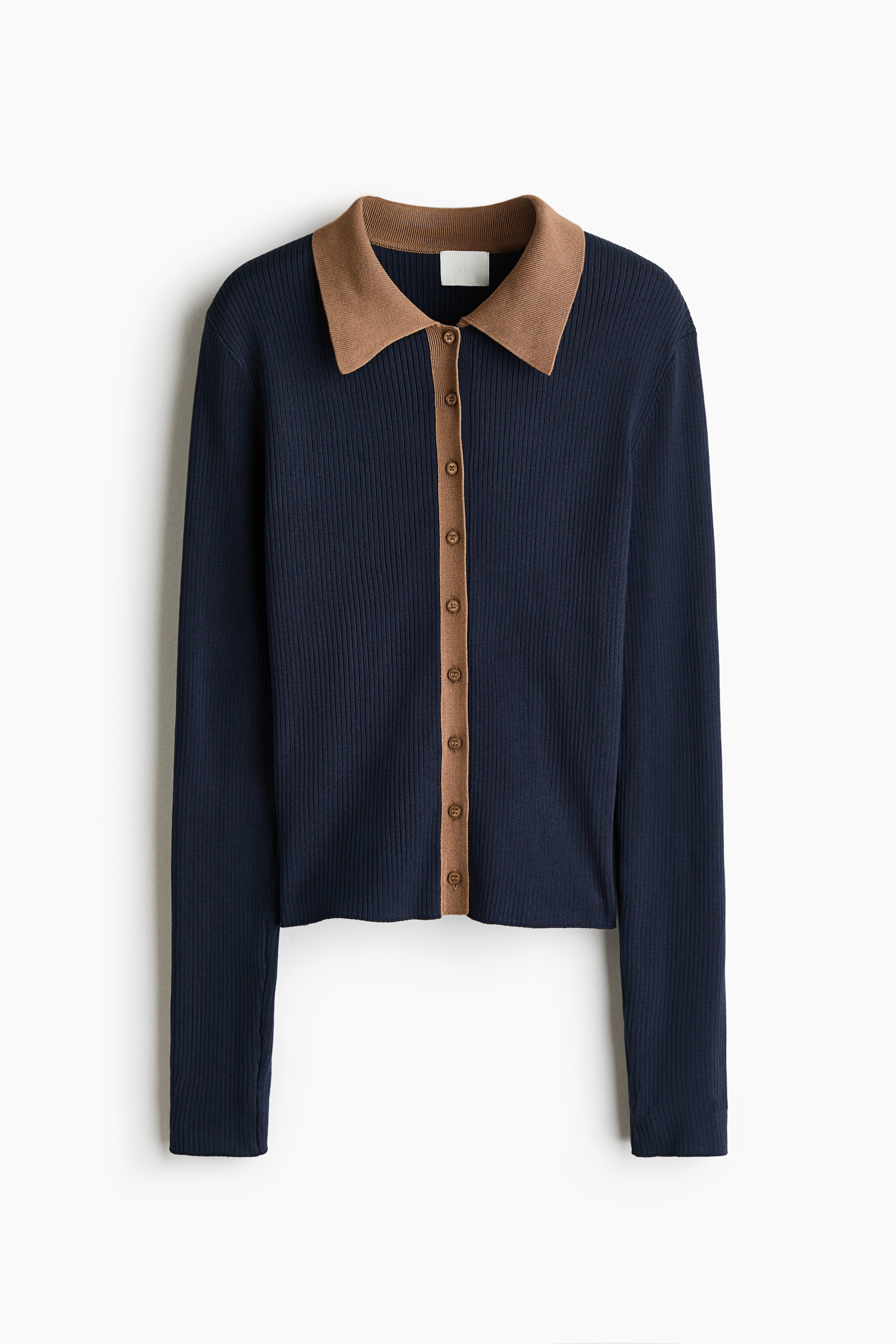 A dark blue rib-knit cardigan featuring a contrasting light brown collar and button band is being worn by the model. The cardigan is partially unbuttoned at the neck, showing a red ribbed top layered underneath.