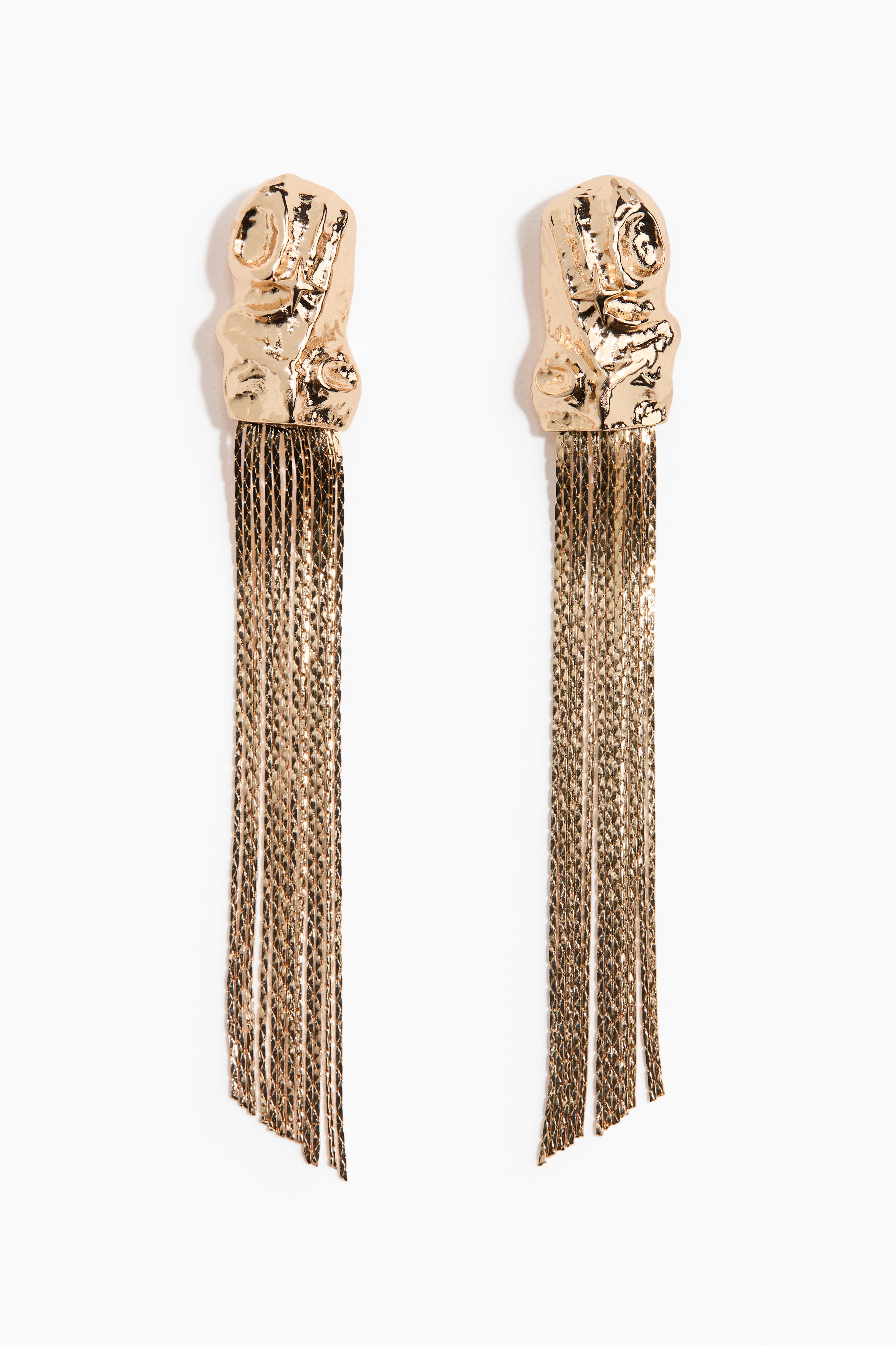 Gold-toned metal dangle earrings featuring a textured, organic-shaped top piece and long, fine metal strands are worn by the model. The cascading strands fall toward the collarbone and are styled with a draped cream garment.