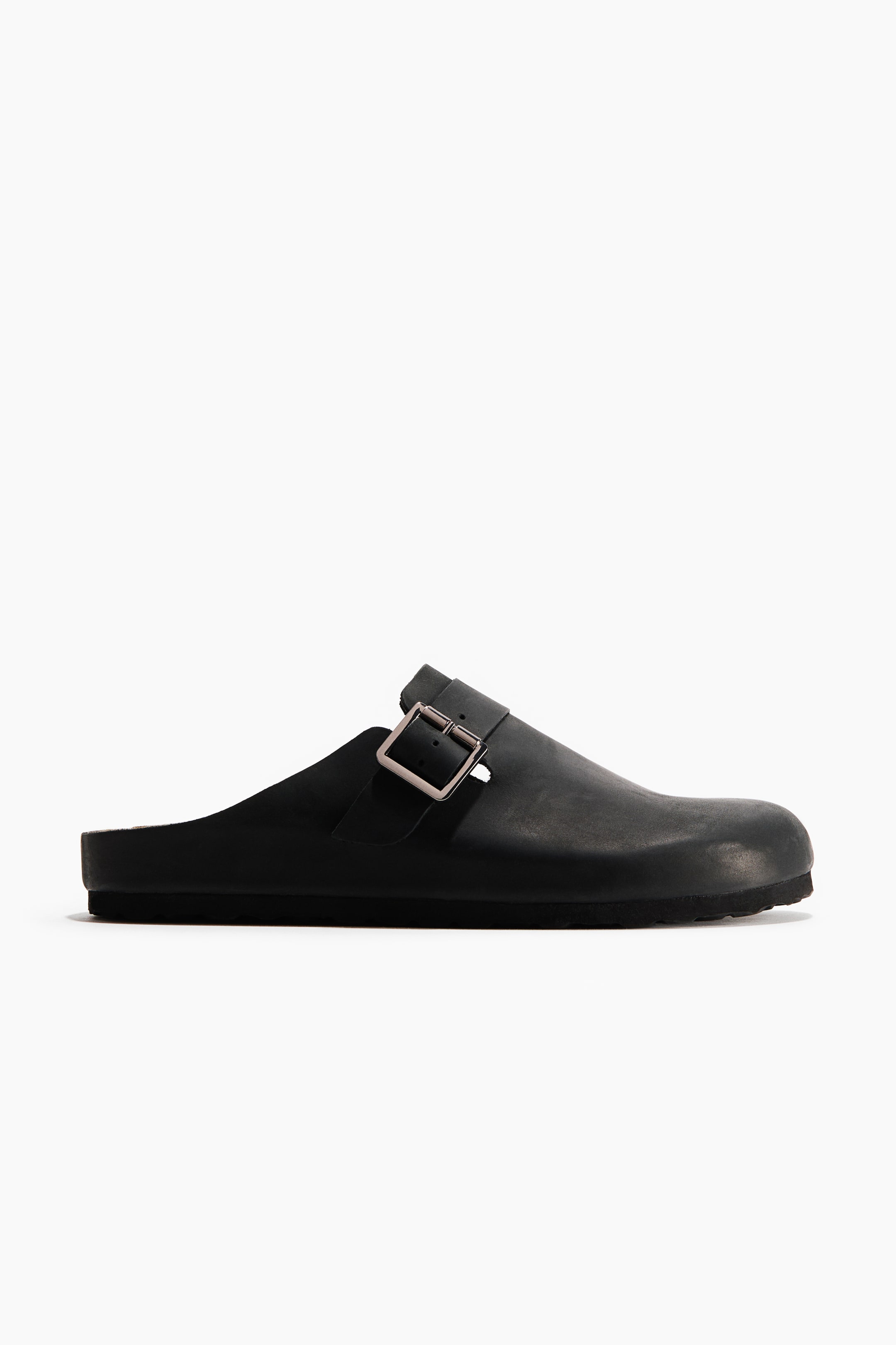 View larger image: A black clog is facing left, showcasing a matte upper with a closed toe. A strap extends across the instep, secured by a rectangular silver-toned buckle.
