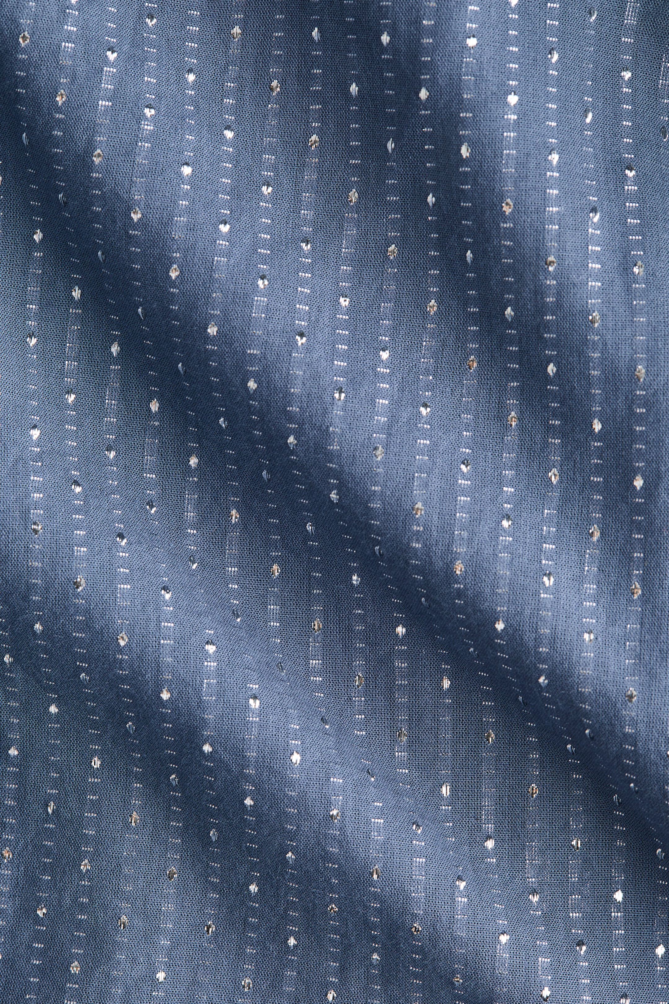 Agrandir l'image: Le tissu présente une couleur de base bleu-gris, avec des rayures verticales formées par l'alternance de petits points métalliques brillants et de fines lignes de coutures blanches. Le textile se drape en plis doux.