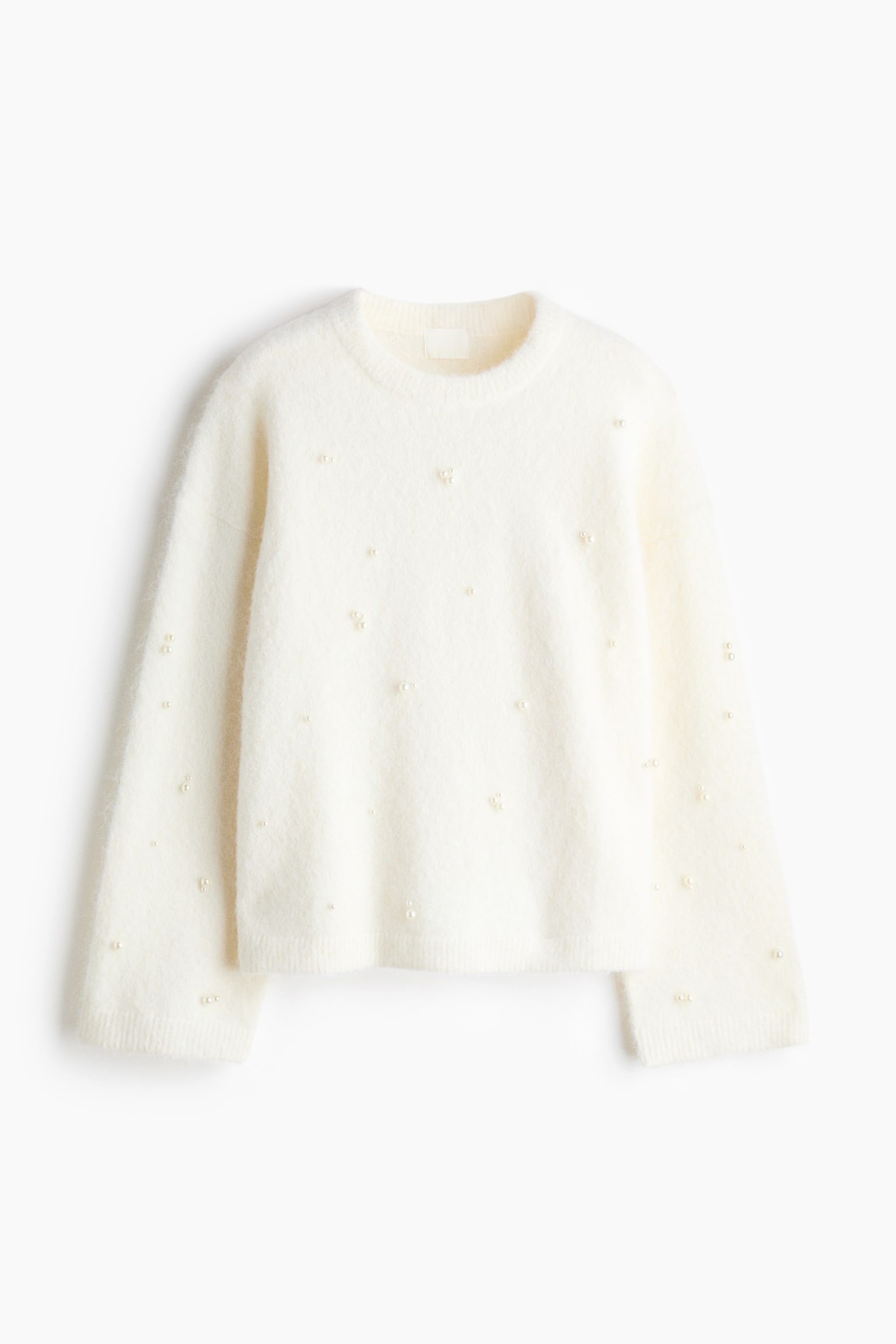 Ein cremefarbener, flauschiger Strickpullover ist von vorne zu sehen und prÃ¤sentiert verstreute Kunstperlen-Verzierungen auf der Vorderseite des Oberteils sowie an den langen Ãrmeln. Der Pullover verfÃ¼gt Ã¼ber einen gerippten Rundhalsausschnitt, leicht weite Ãrmel und einen gerippten Saum.