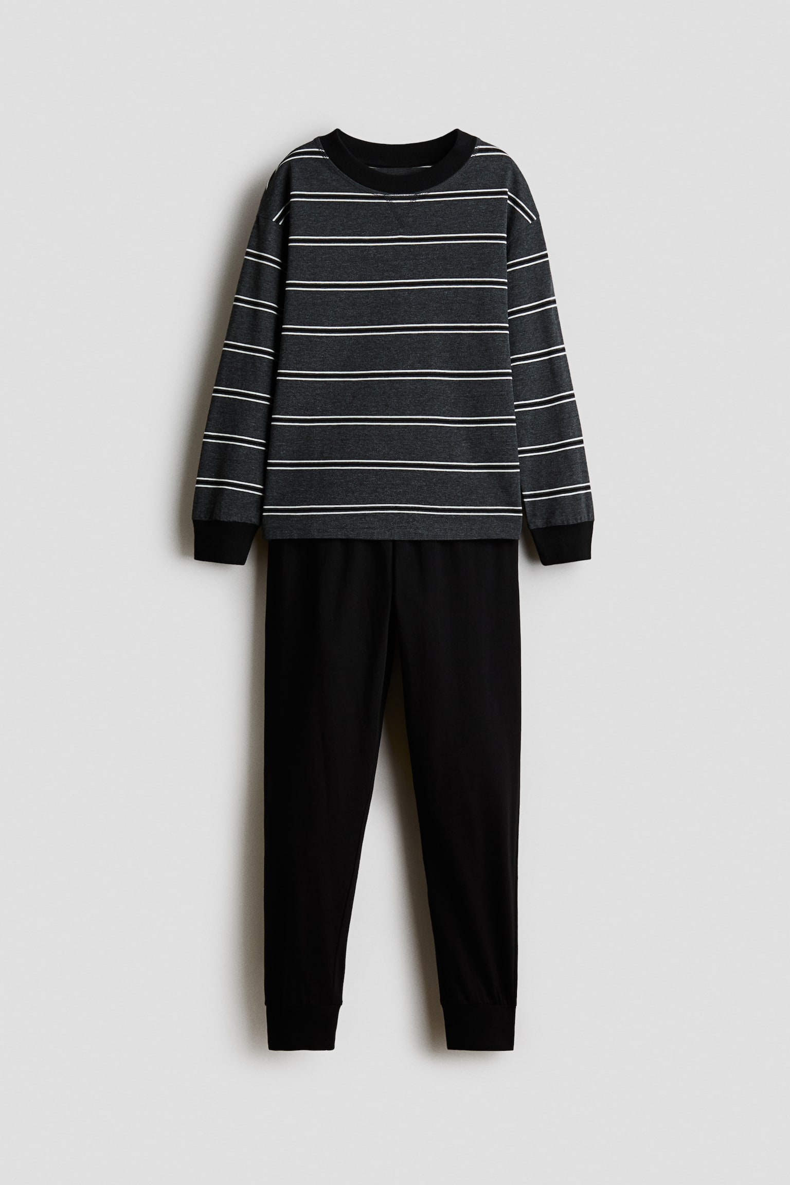 Eine frontale Ansicht eines Pyjama-Sets mit einem dunkelgrauen Langarmoberteil mit horizontalen weiÃen Streifen und einer dazu passenden einfarbig schwarzen Hose. Das Oberteil verfÃ¼gt Ã¼ber einen gerippten Rundhalsausschnitt mit kleinem V-Nahtdetail, Ã¼berschnittene Schultern und schwarze gerippte BÃ¼ndchen, wÃ¤hrend die Hose eine zulaufende Passform mit gerippten KnÃ¶chelbÃ¼ndchen aufweist. - 1