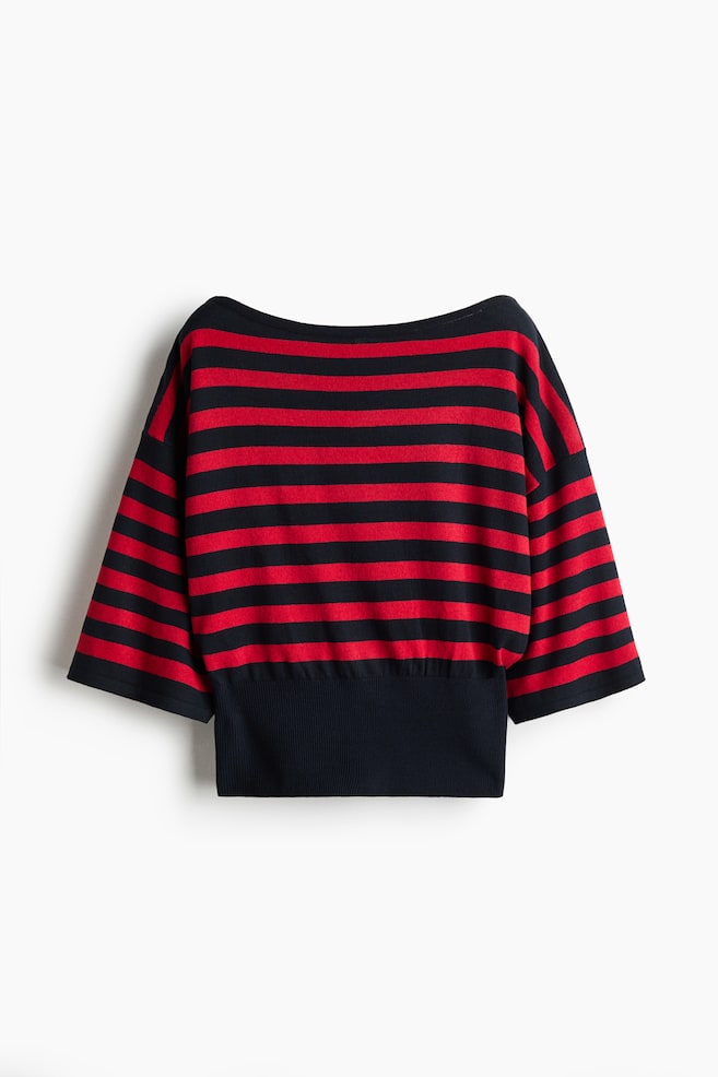 Een rood-zwart gebreid topje met horizontale strepen is van voren afgebeeld, met een brede boothals en losse, driekwartmouwen met verlaagde schoudernaden. Het blousonmodel loopt taps toe in een brede, effen zwarte geribde tailleband. - 1