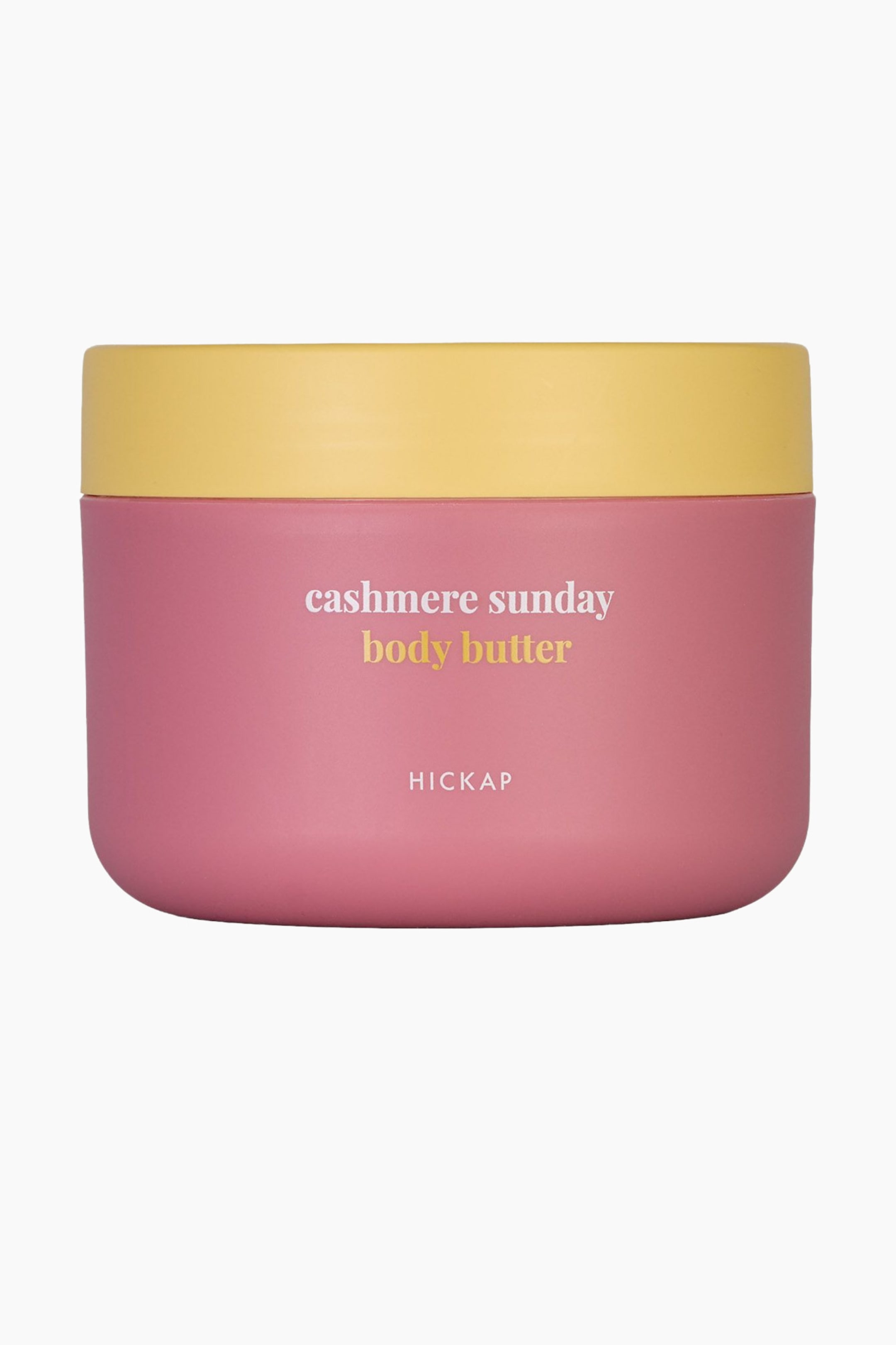Se større billede: En krukke med bodybutter præsenterer en lyserød bund med et gult låg, vendt fremad. Krukken viser "cashmere sunday body butter" og "HICKAP" i hvid tekst på forsiden.