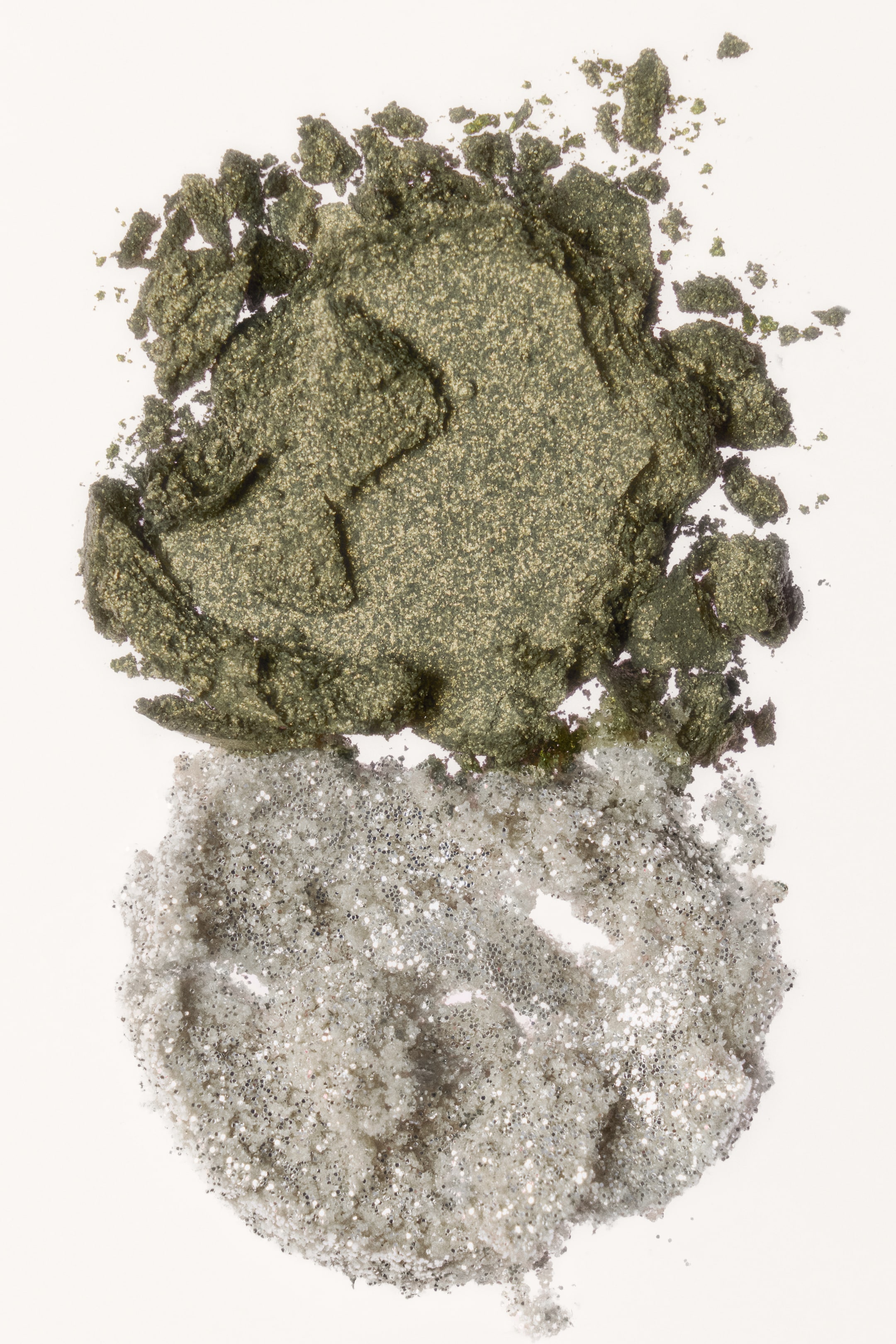 Ampliar la imagen: Este dúo de sombras para ojos se presenta como dos montículos texturizados y triturados apilados verticalmente. El montículo superior muestra un tono satinado verde oliva con un fino brillo dorado, mientras que el montículo inferior exhibe un topper de glitter plateado, brillante y reflectante.
