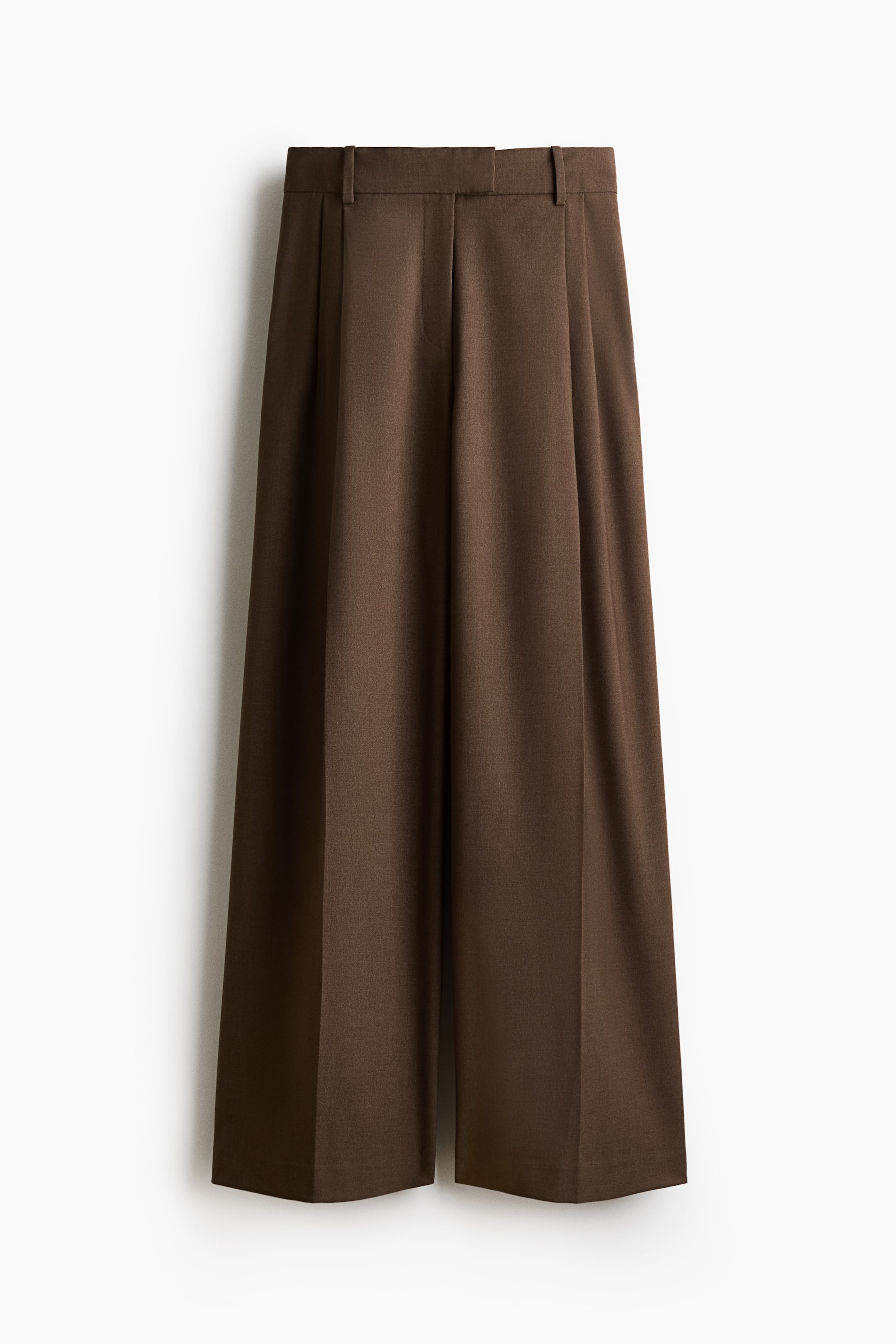 View larger image: Brown trousers feature a flat waistband with belt loops, double front pleats, and a wide-leg cut. Creases run down the centre front of each leg.