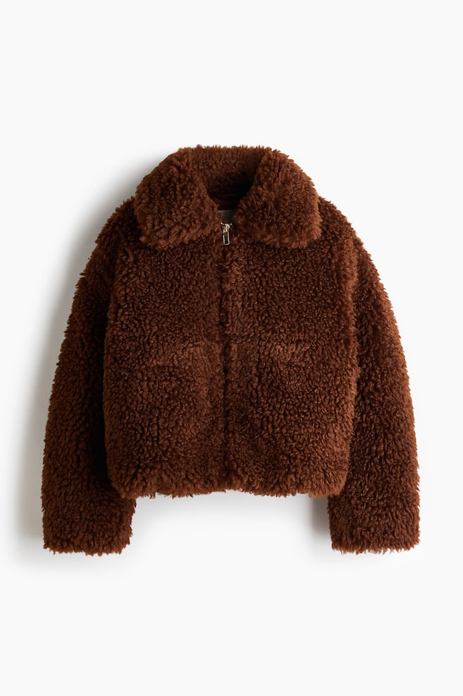 A brown teddy fleece jacket is displayed from the front, featuring a wide, spread collar and a metallic zipper closure down the center. It is designed with long sleeves and a cropped hem. - 1