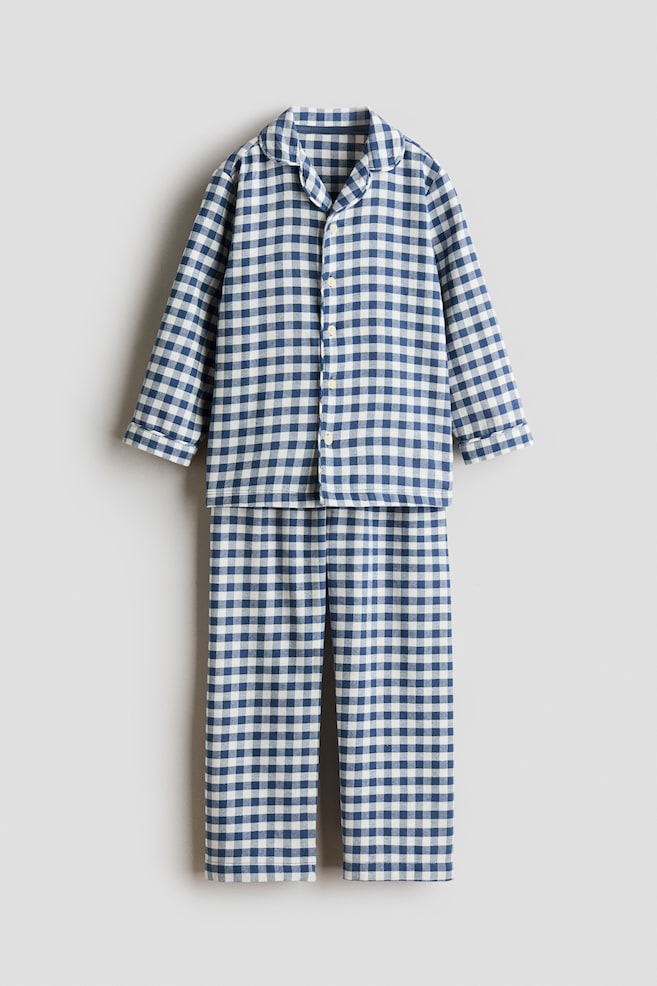 Un set de pijama Ã®n carouri alb-albastre este agÄÈat, vÄzut din faÈÄ, format dintr-o cÄmaÈÄ cu mÃ¢necÄ lungÄ, cu nasturi, guler rÄsfrÃ¢nt Èi pantaloni drepÈi asortaÈi. - 1