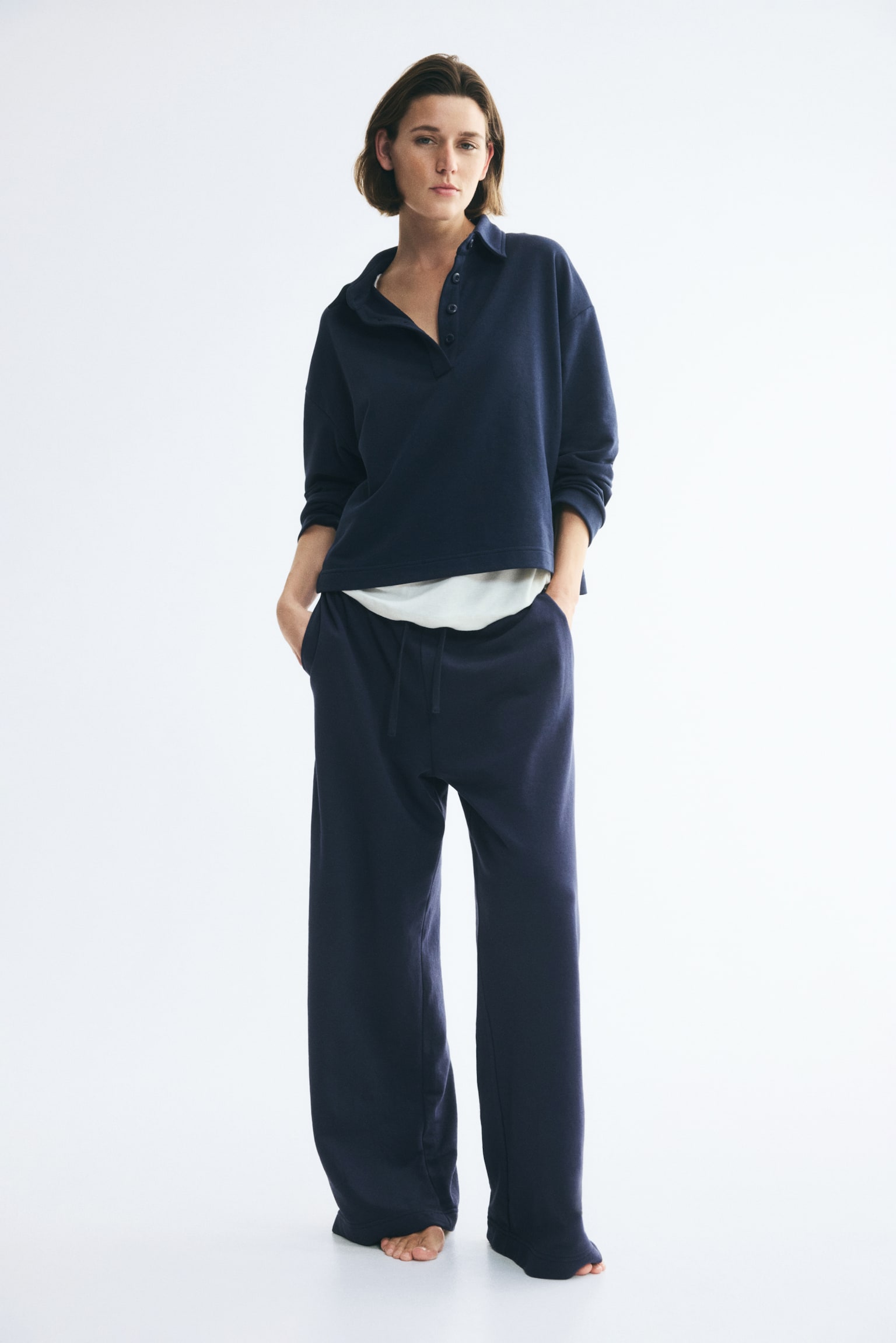 Navy blue joggers are showcased from a front perspective, highlighting an elasticated waistband with a drawstring fastening. These joggers are crafted with straight legs in a lightweight sweatshirt material. - 1