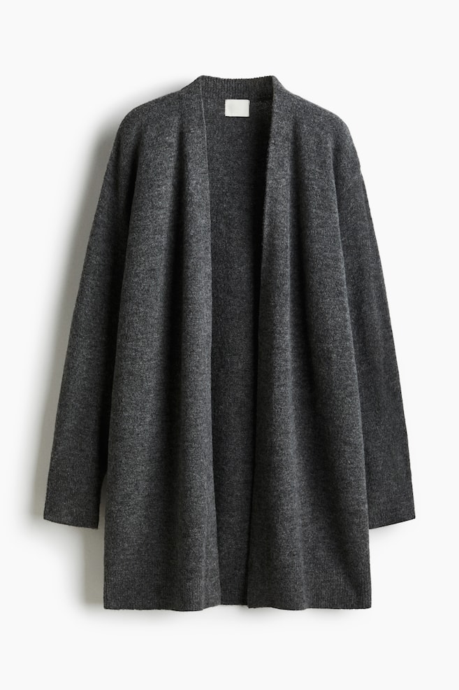 Un long cardigan gris foncé affiche son DEVANT, mettant en valeur une texture de tricot fin. Il présente un devant ouvert sans boutons, des épaules tombantes et des manches longues, avec un bord-côte visible aux poignets, à l'ourlet et autour de l'arrière du cou. - 1