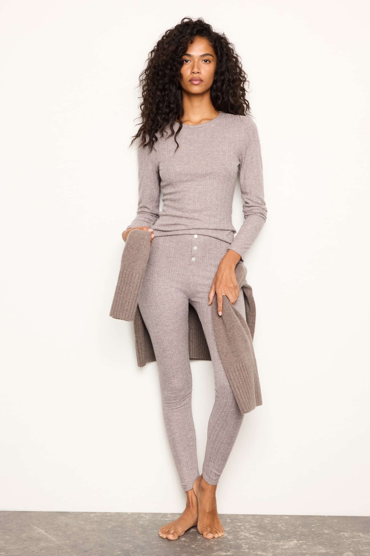 Un ensemble pyjama deux piÃ¨ces en jersey pointelle texturÃ© couleur taupe est prÃ©sentÃ© de face, comprenant un haut Ã  manches longues et un legging slim assorti. Le haut est dotÃ© dâun col rond, et les deux piÃ¨ces prÃ©sentent de subtils dÃ©tails de finition picot au niveau de lâencolure, des poignets et des ourlets. - 1
