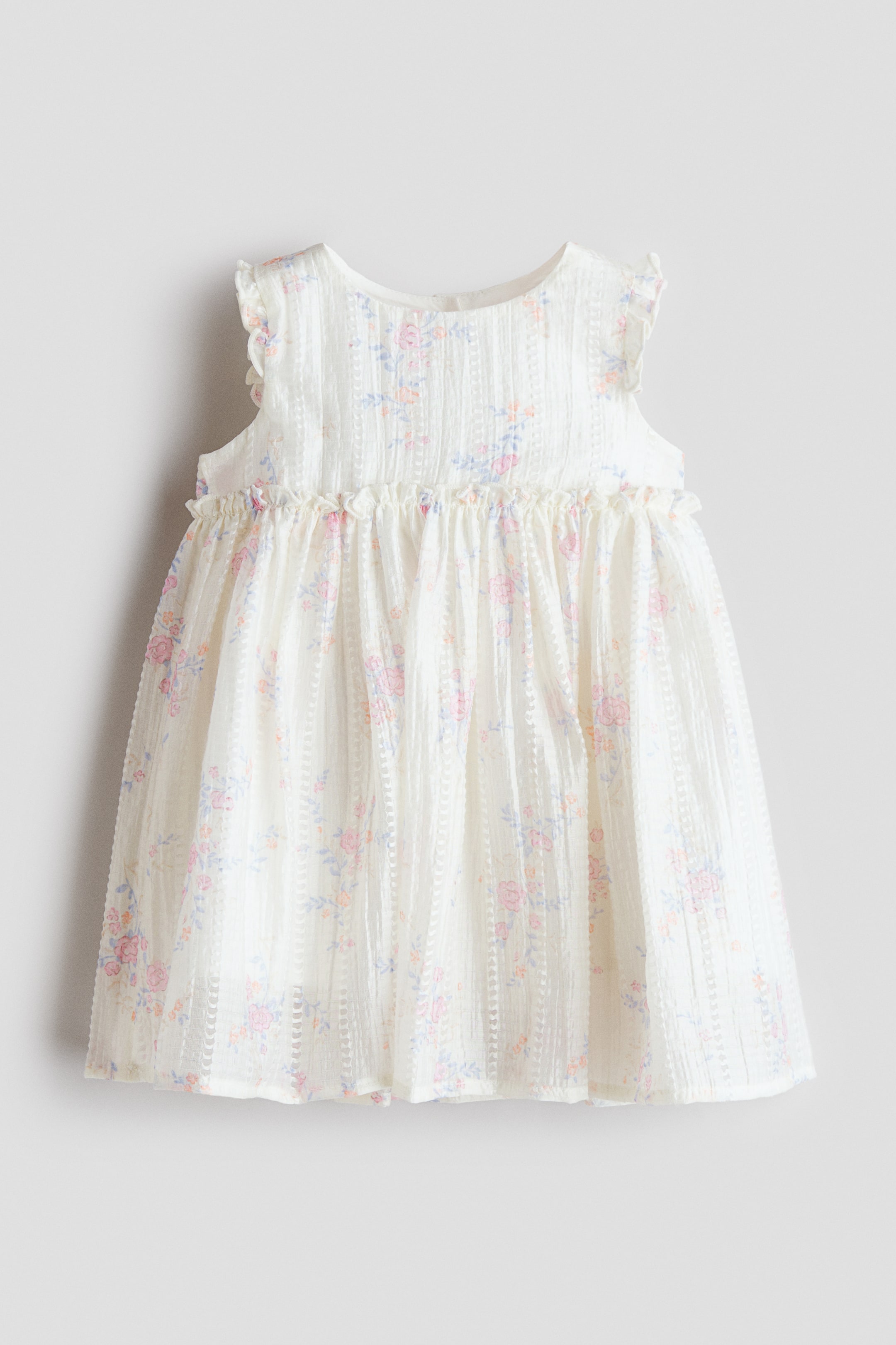 View larger image: The sleeveless dress is featured as front, showcasing a sheer, textured weave with an all-over floral print in pink, blue, and orange hues, and is crafted with a round neckline. It highlights narrow frill trims over the shoulders and above the gathered waist, flowing into a flared skirt, and is lined.