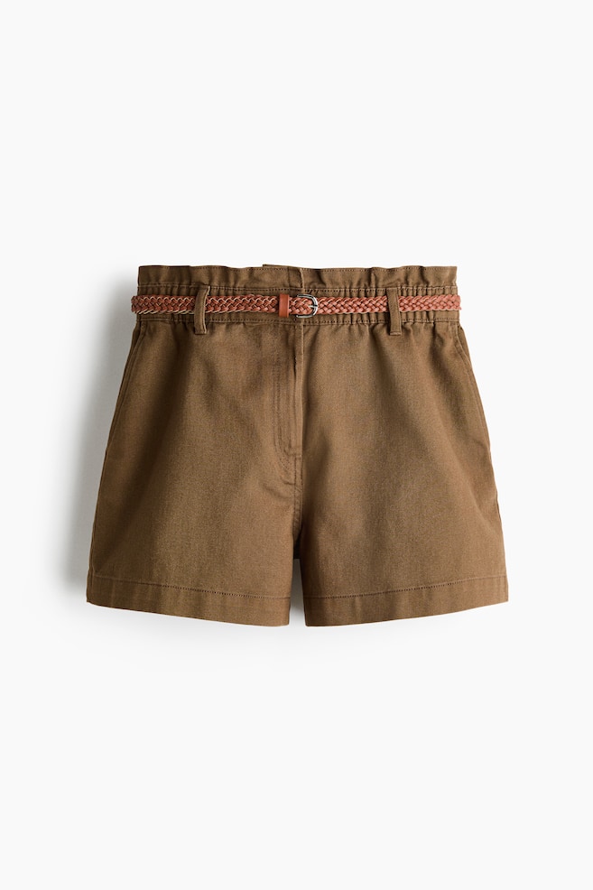 Braune Shorts mit Paperbag-Taille, einem geflochtenen braunen Gürtel und einer silbernen Schnalle. Sie sind mit seitlichen Fronttaschen und einem umgeschlagenen Saum gestaltet. - 1