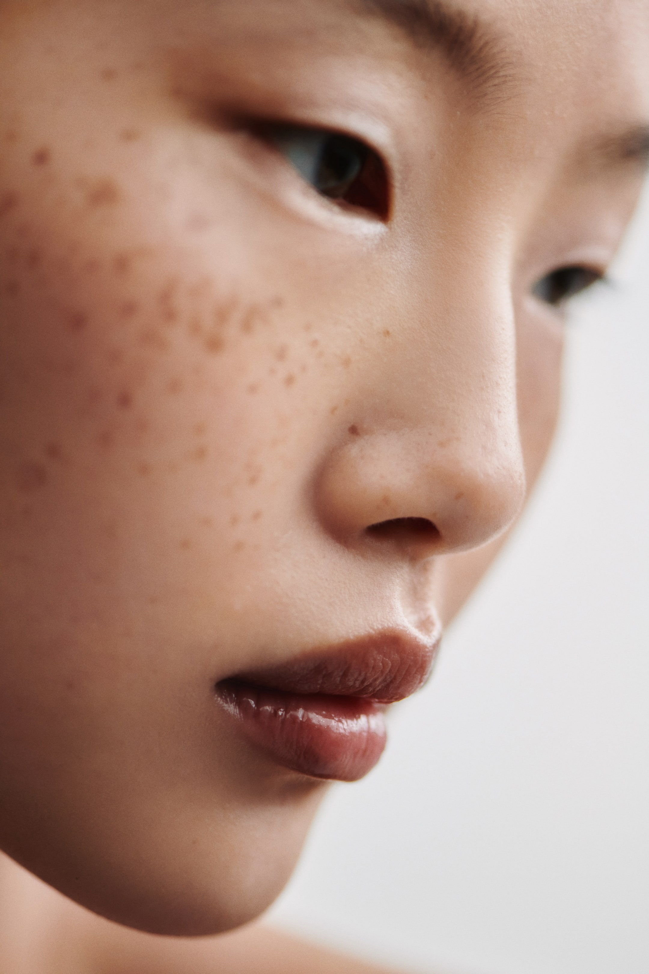 Größeres Bild ansehen: Ein bräunlich-roter Lipgloss verleiht den Lippen ein volles und glänzendes Finish, die nach unten und nach rechts geneigt sind.