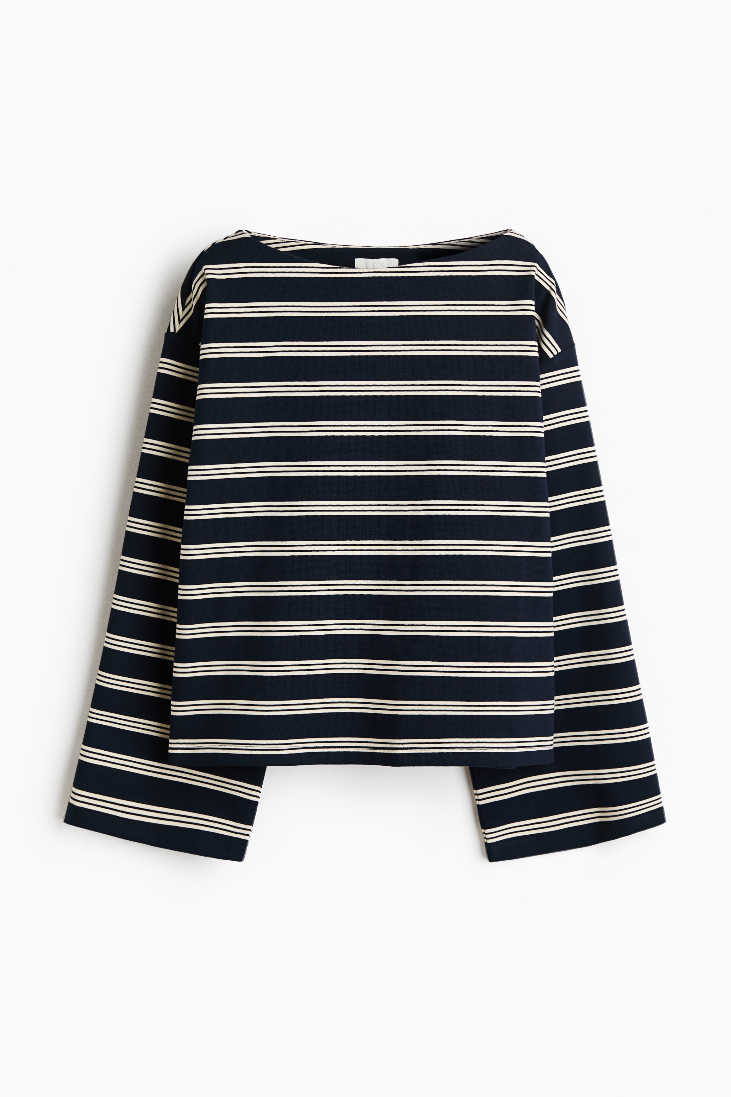 An oversized striped top in a lightweight jersey featuring a boat neck and long, wide sleeves is being worn by the model. The top is layered over a white long-sleeved shirt and styled with black wide-leg trousers.