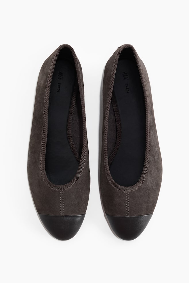 Deux ballerines en daim brun foncé sont dotées de bouts noirs et de semelles intérieures noires. Une bordure côtelée brun foncé souligne l'ouverture de chaque chaussure. - 1