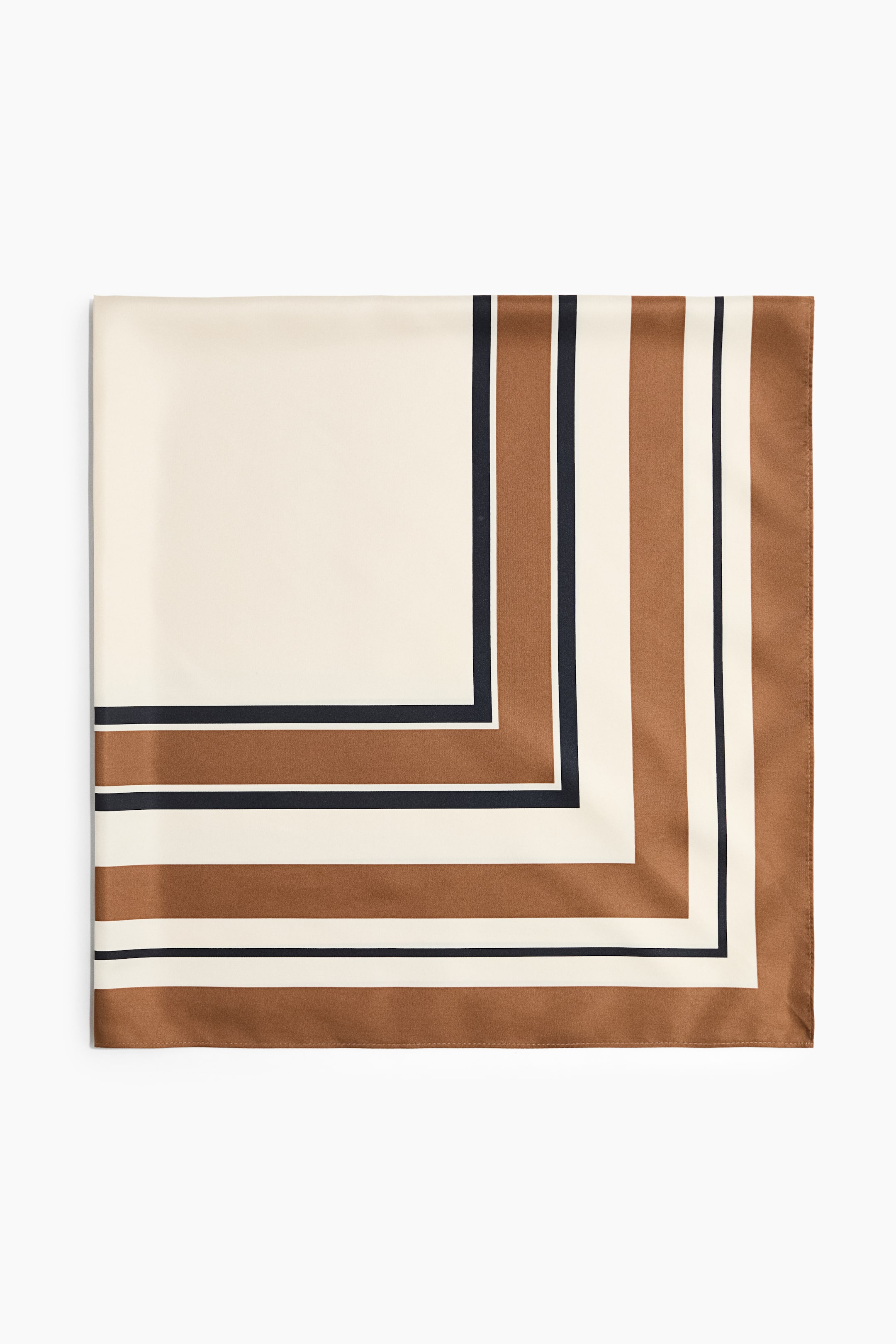 Größeres Bild ansehen: Ein quadratisches Tuch in weicher Webart liegt flach und mit der Vorderseite nach oben und zeigt ein gedrucktes geometrisches Muster. Das Design weist in einer Ecke einen einfarbigen cremefarbenen Block auf, der von abwechselnden Streifen in Braun, Marineblau und Creme eingefasst ist.