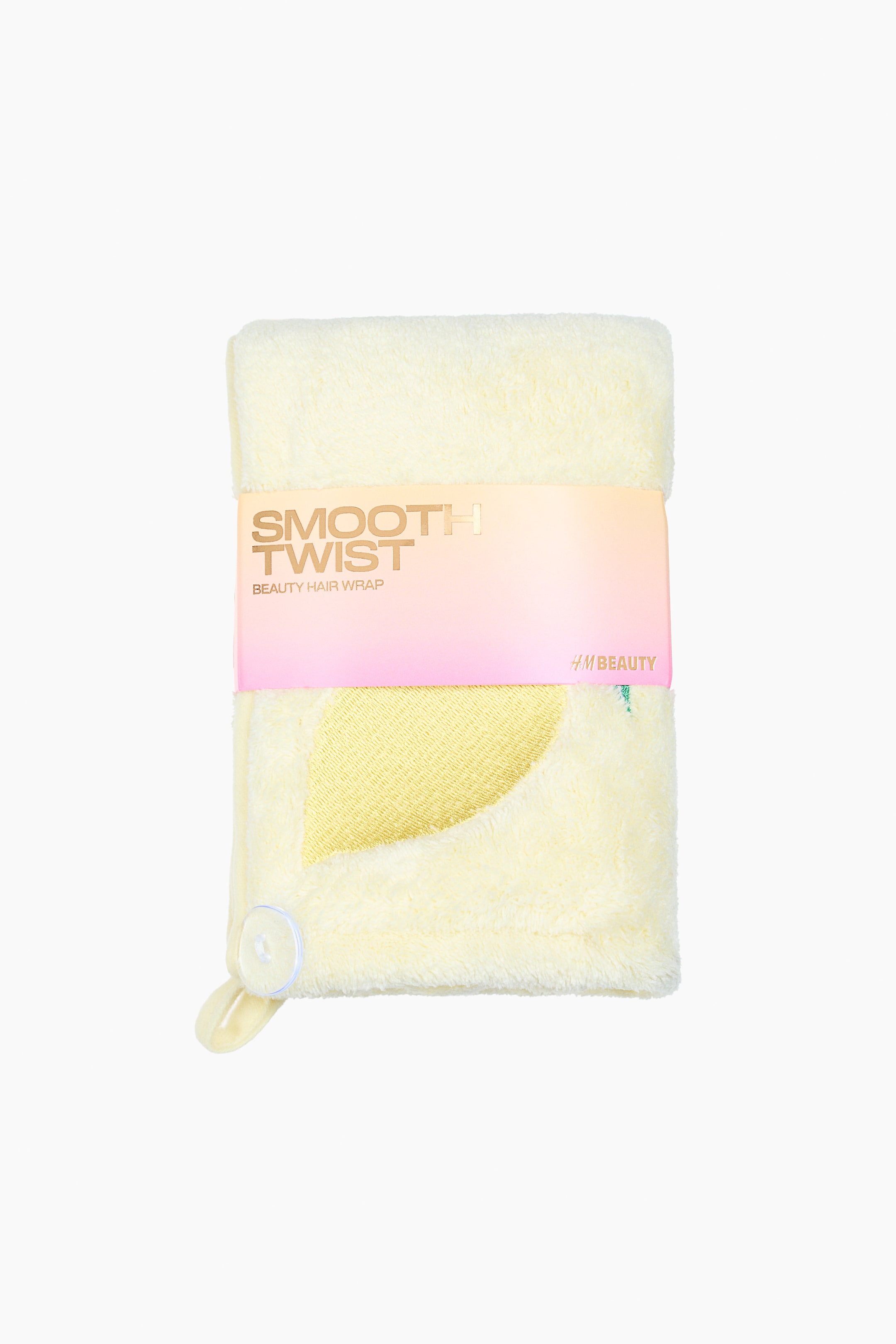 Ver imagem maior: Um turbante de cabelo em microfibra amarelo está voltado para a frente, dobrado e apresentado com uma faixa em degradê rosa e laranja exibindo o texto "SMOOTH TWIST BEAUTY HAIR WRAP". Apresenta um design bordado de folha amarela e um botão transparente com um laço de tecido, indicando o seu fecho.