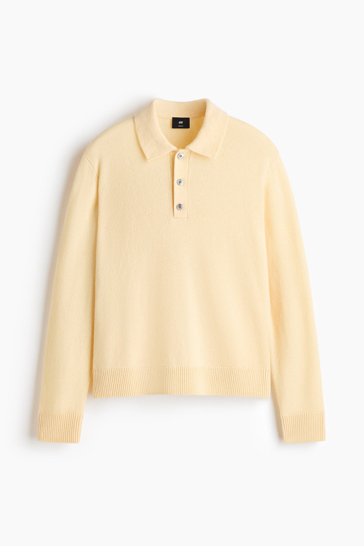 A pale yellow, fine-knit polo shirt is shown from the front, featuring a classic polo collar, a three-button placket, and long sleeves. The garment showcases a regular-fit silhouette with ribbed detailing at the cuffs and hem. - 1