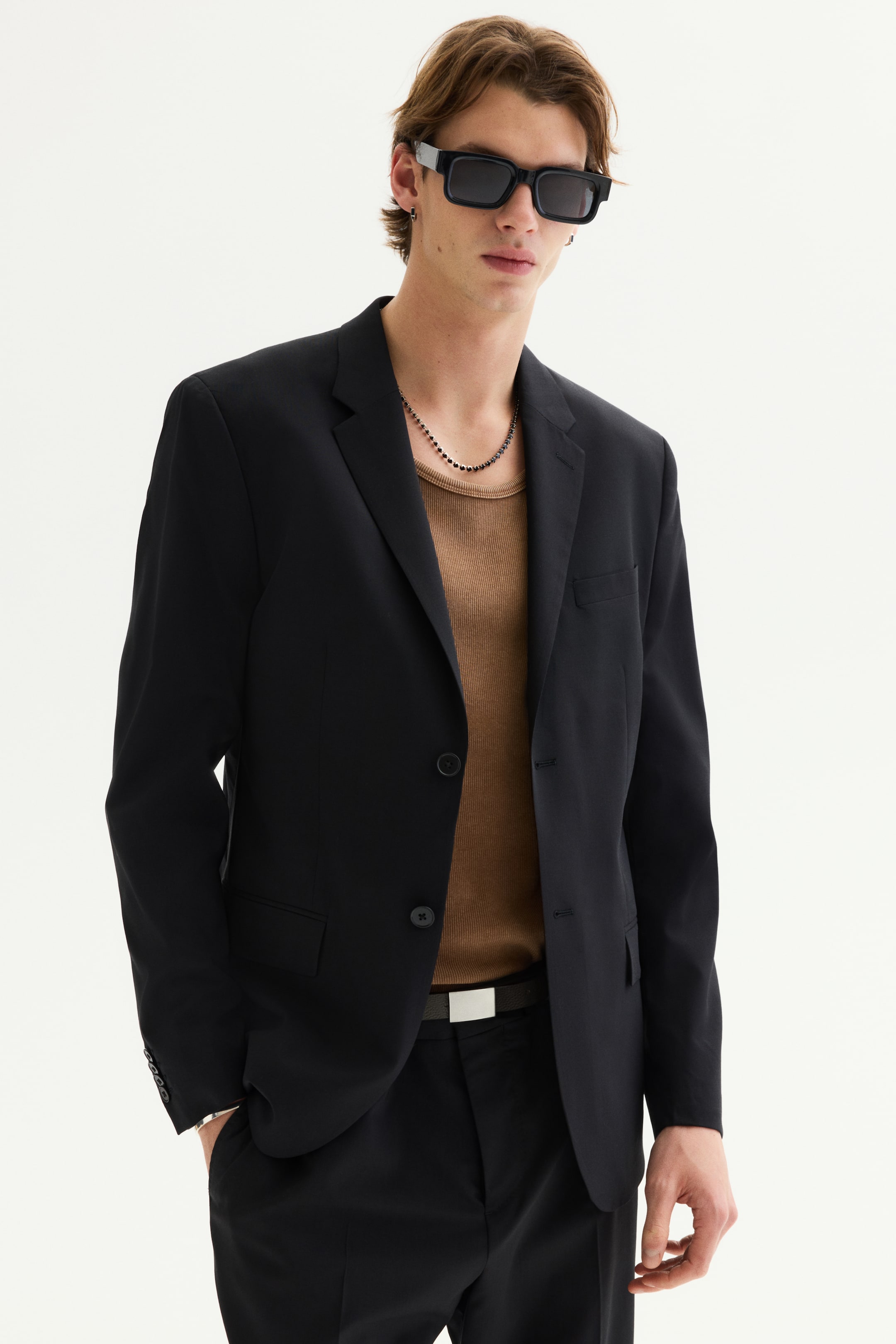View larger image: A black blazer is displayed from a slight front-right angle, showcasing notch lapels and a two-button closure with the top button fastened. It also features flap pockets, a welt chest pocket, and three buttons on each cuff.