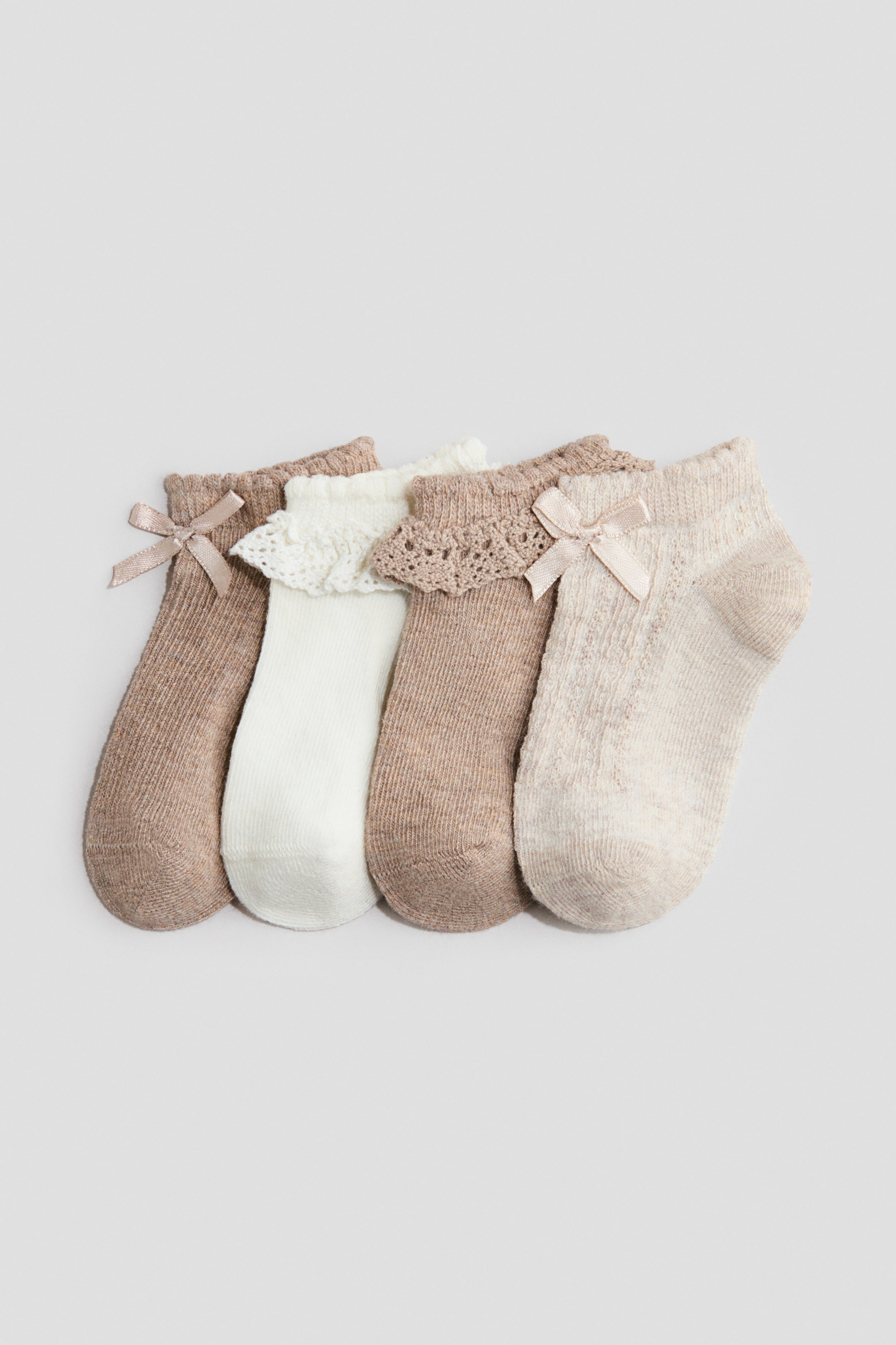 הצגת תמונה גדולה יותר: חמישה זוגות גרביים ללא גבעול מסודרים בשורה, מציגים גימורים אלסטיים עם פרטים דקורטיביים. הגרביים מציגים תערובת של צבעים ניטרליים, כולל לבן-שבור, חום בהיר ובז', כאשר חלקם מעוטרים בקשתות סאטן קטנות ואחרים עם תחרה מסולסלת או סרוגה.