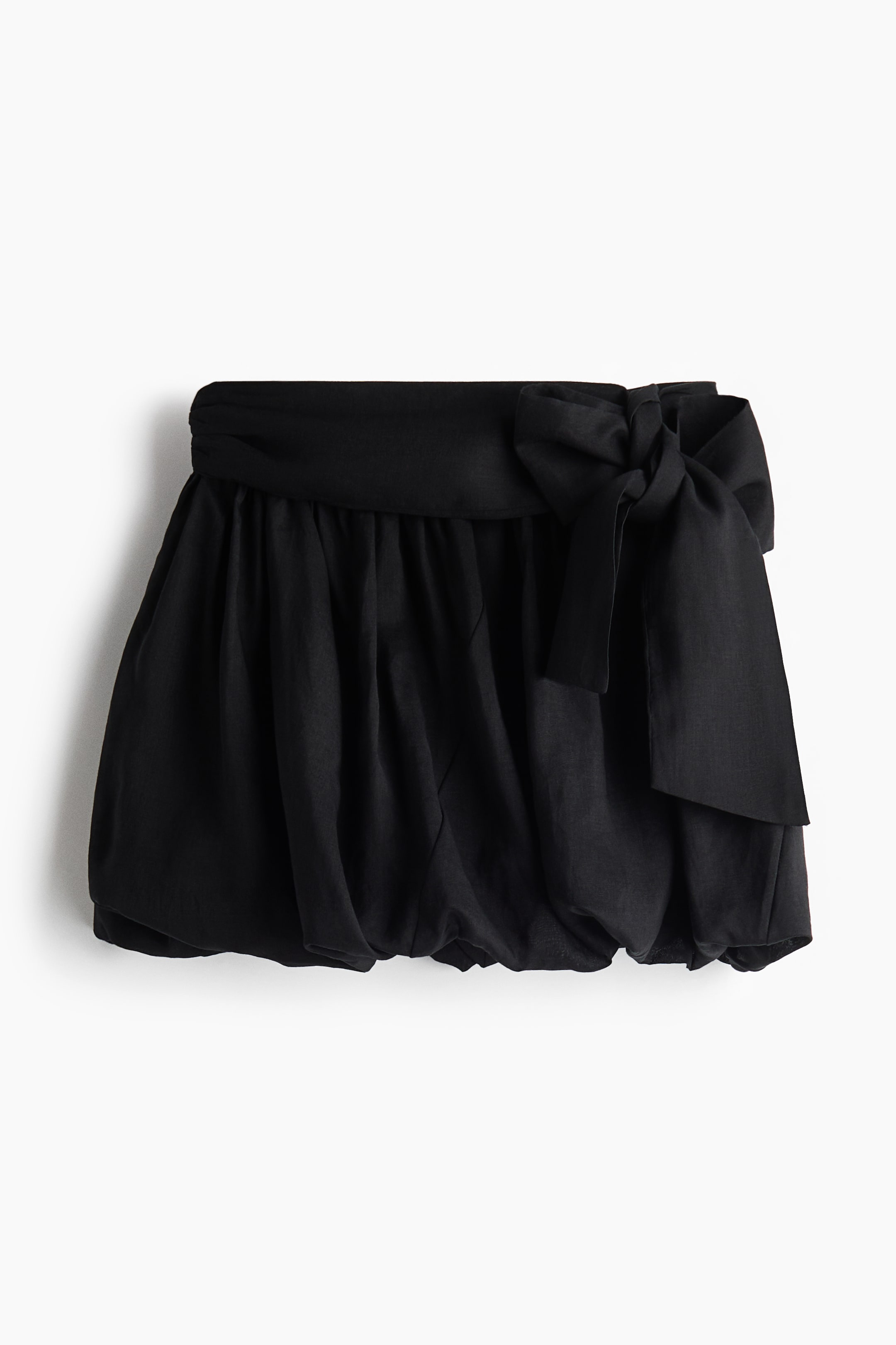 Ver imagen más grande: Los pantalones cortos globo negros presentan una cintura ancha fruncida, de la cual se forma un gran lazo en el lado derecho. Los pantalones cortos muestran una silueta voluminosa con fruncidos en el dobladillo.