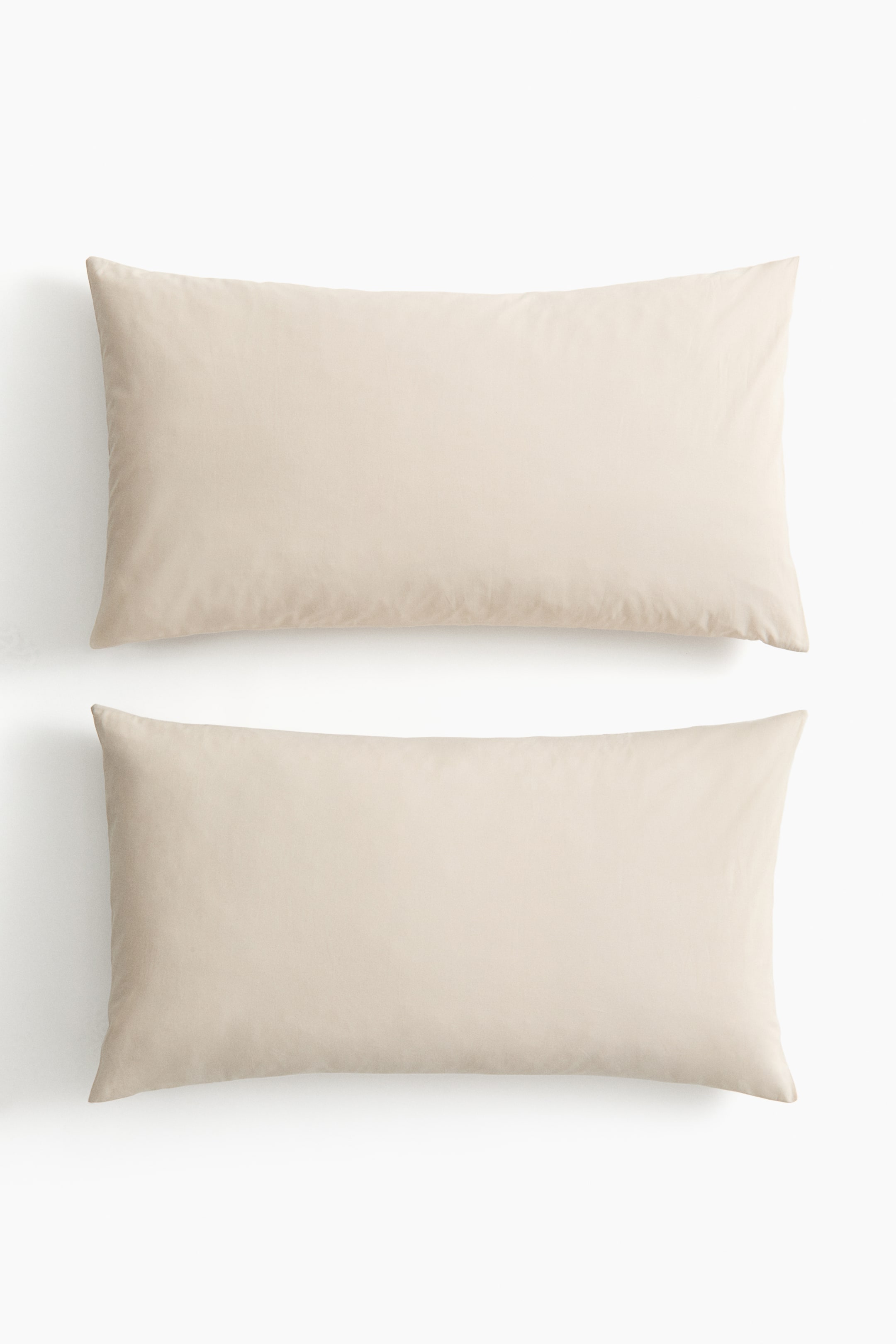 View larger image: A pair of light beige pillowcases lie flat, one atop the other, displaying a soft cotton weave and an envelope opening.