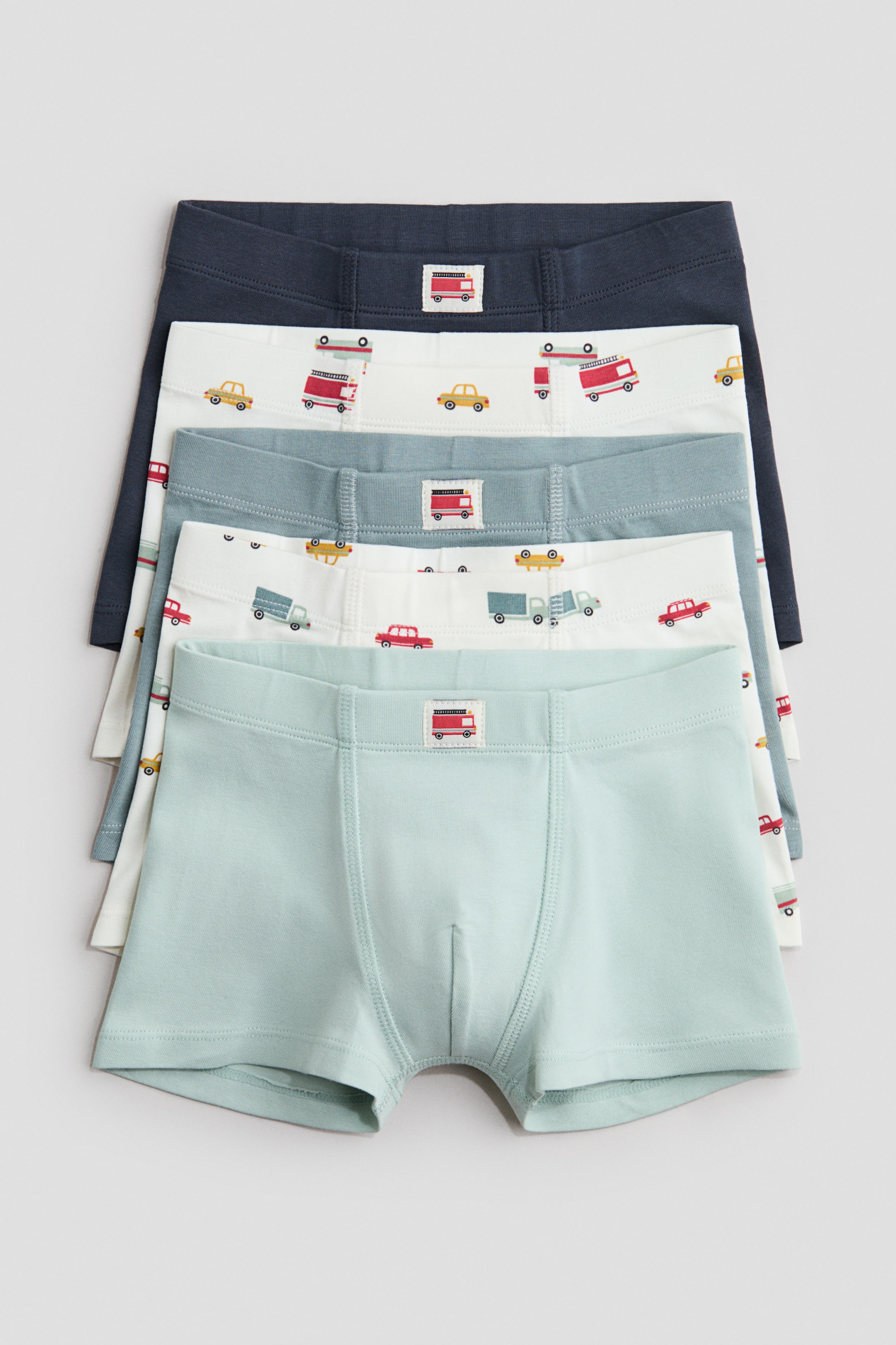 View larger image: Trunks in cotton jersey with short legs, an elasticated waist, and a lined front are presented as a stacked set of five, with the FRONT angle visible. The set includes plain dark blue and light green trunks, along with white and light blue trunks featuring vehicle graphics.