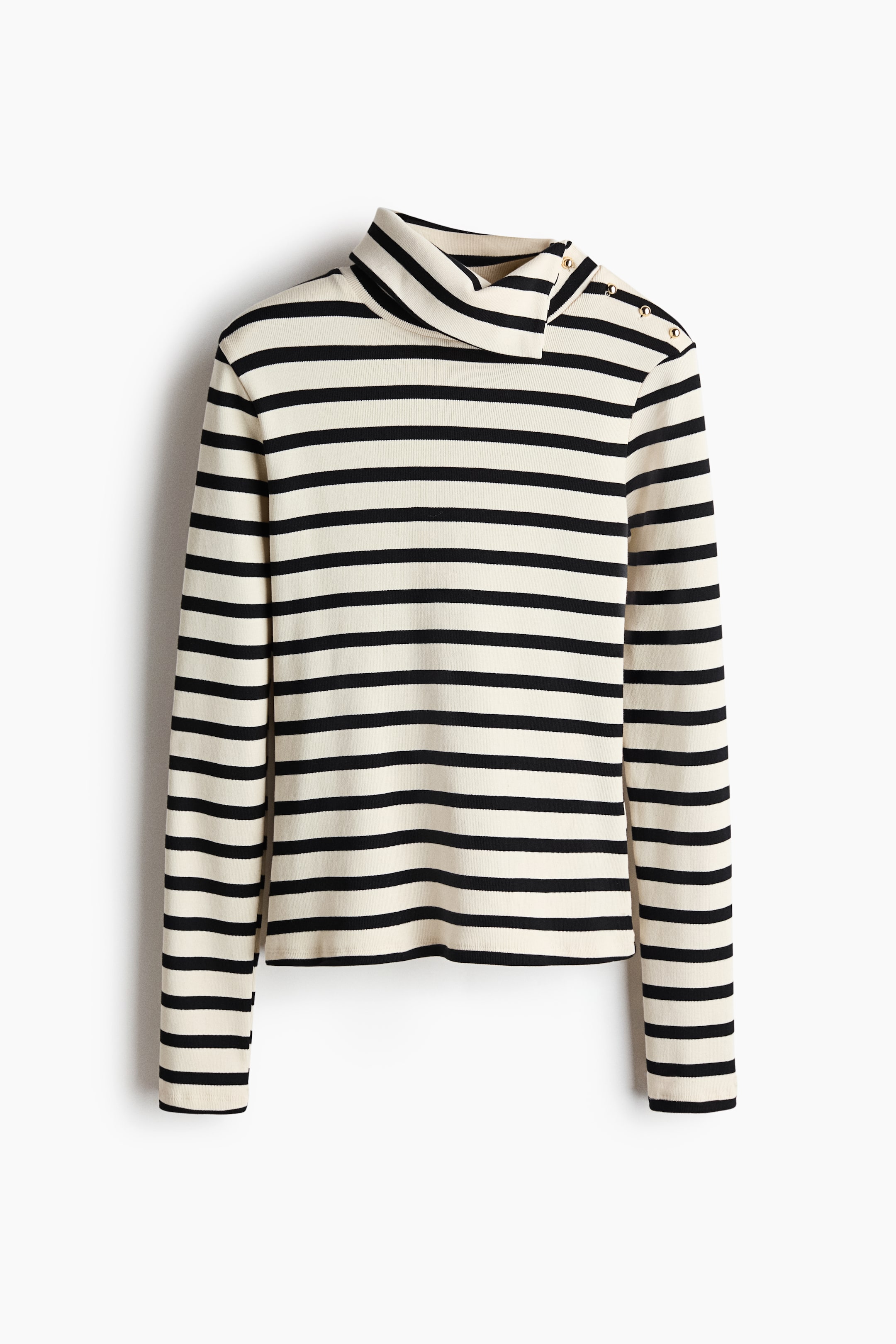 Ampliar la imagen: La blusa a rayas presenta franjas horizontales en color crema y negro. Tiene cuello alto, con botones en tono dorado en el hombro izquierdo y en el cuello, y mangas largas que completan el diseño.