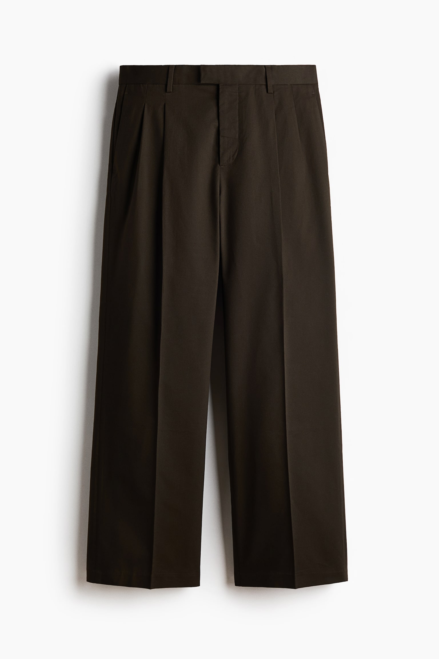 Dark-colored trousers are presenting from the front, featuring an extended waistband with belt loops and a concealed fly closure. They are showcasing a loose fit with subtle side pockets and visible creases running down the front of each leg. - 1
