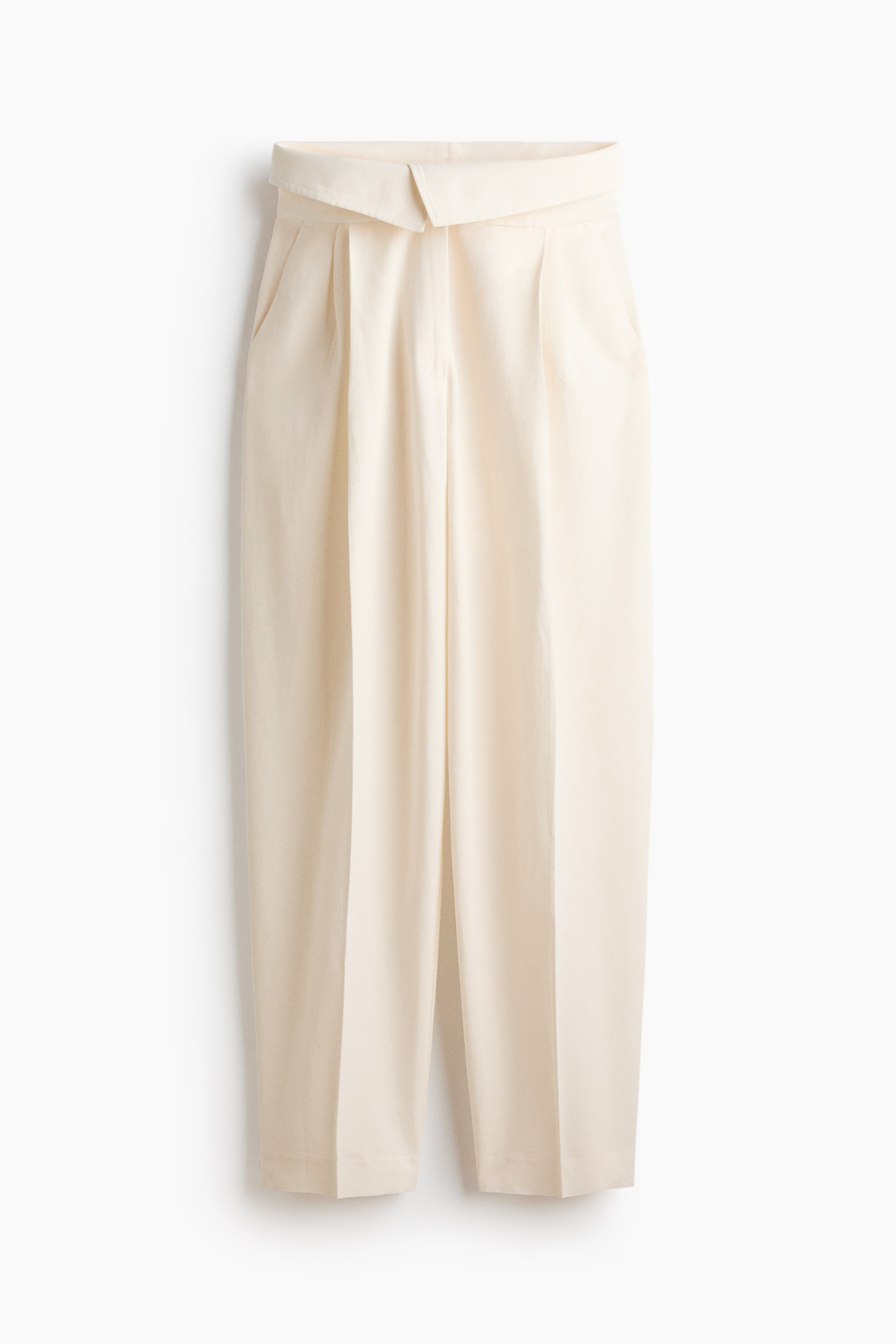 View larger image: Cream-colored pants showcase a high-waisted design with a wide, folded-over waistband and a visible single button closure at the front. They feature double pleats on each leg, integrated side pockets, and a relaxed, cropped fit with a straight hem.