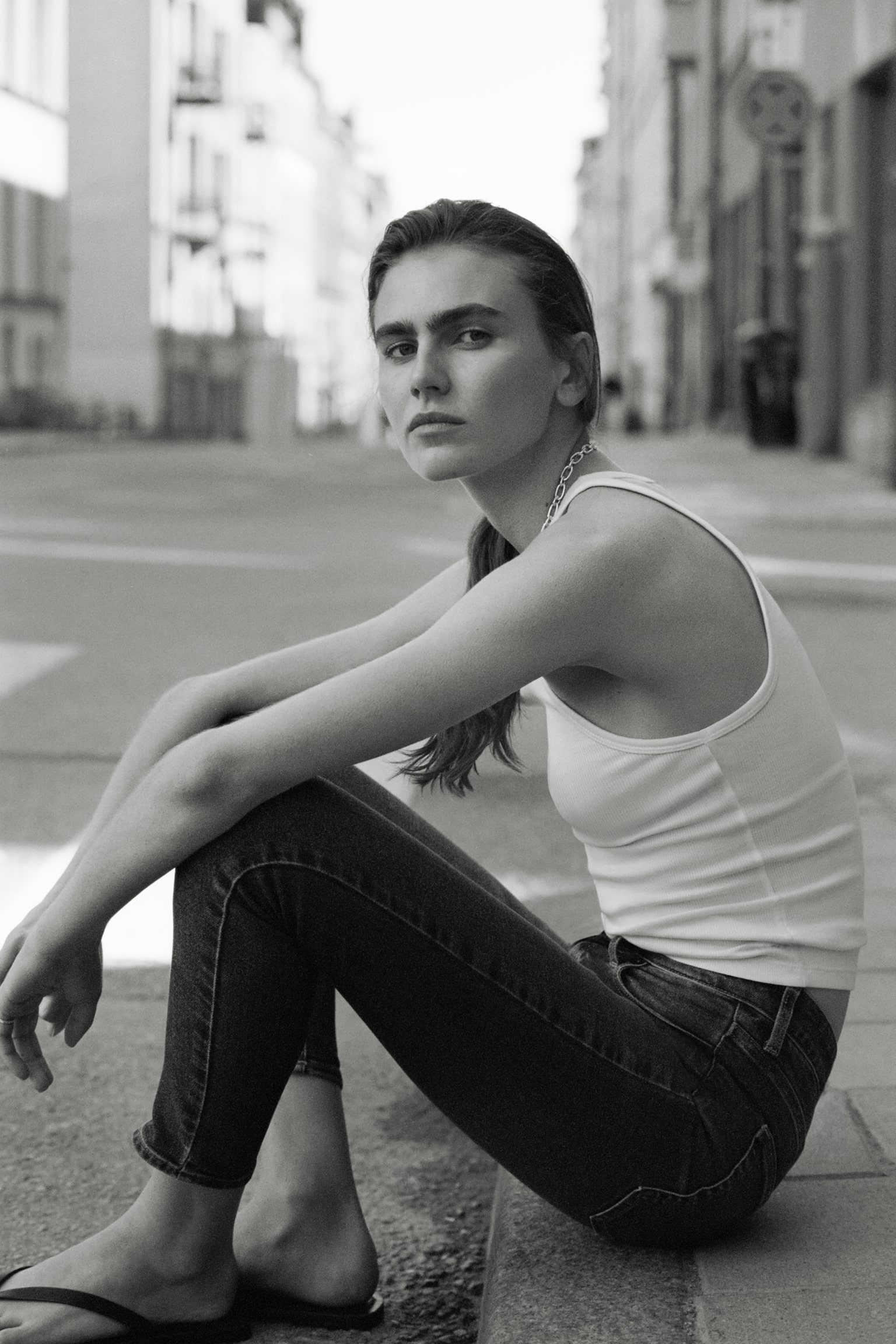 Un jean skinny-fit en denim extensible à 5 poches bleu est présenté de face, avec une taille haute, une fermeture éclair et un bouton, et un délavage moyen affichant des décolorations subtiles sur les cuisses. - 1