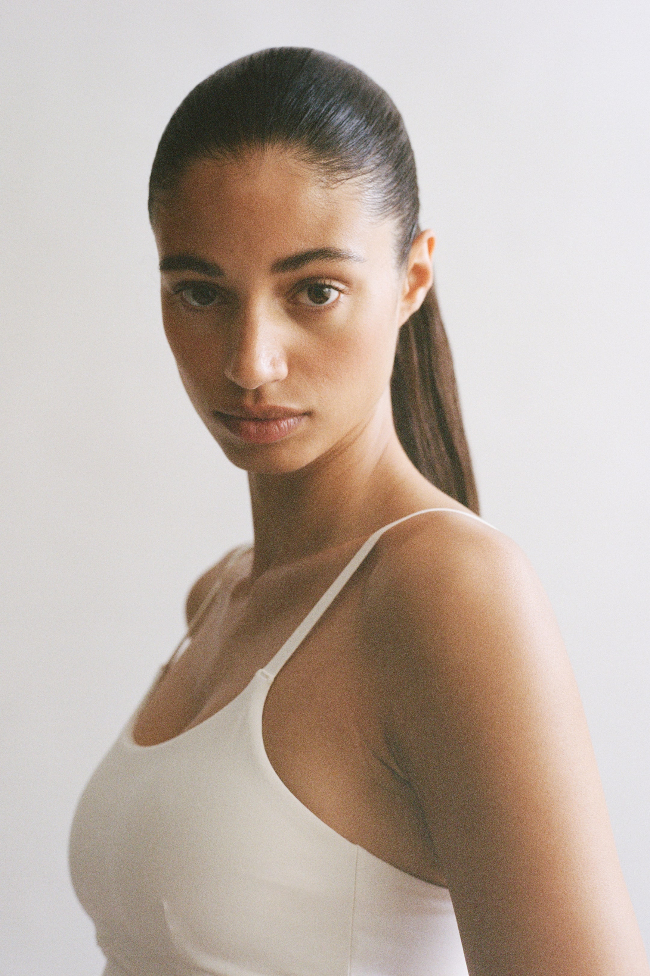 View larger image: The model is showcasing an Integral-bra sports strappy top with SoftMove? technology. This light-hued, scoop-neck top comes with slender adjustable straps and fits snugly to her upper body.