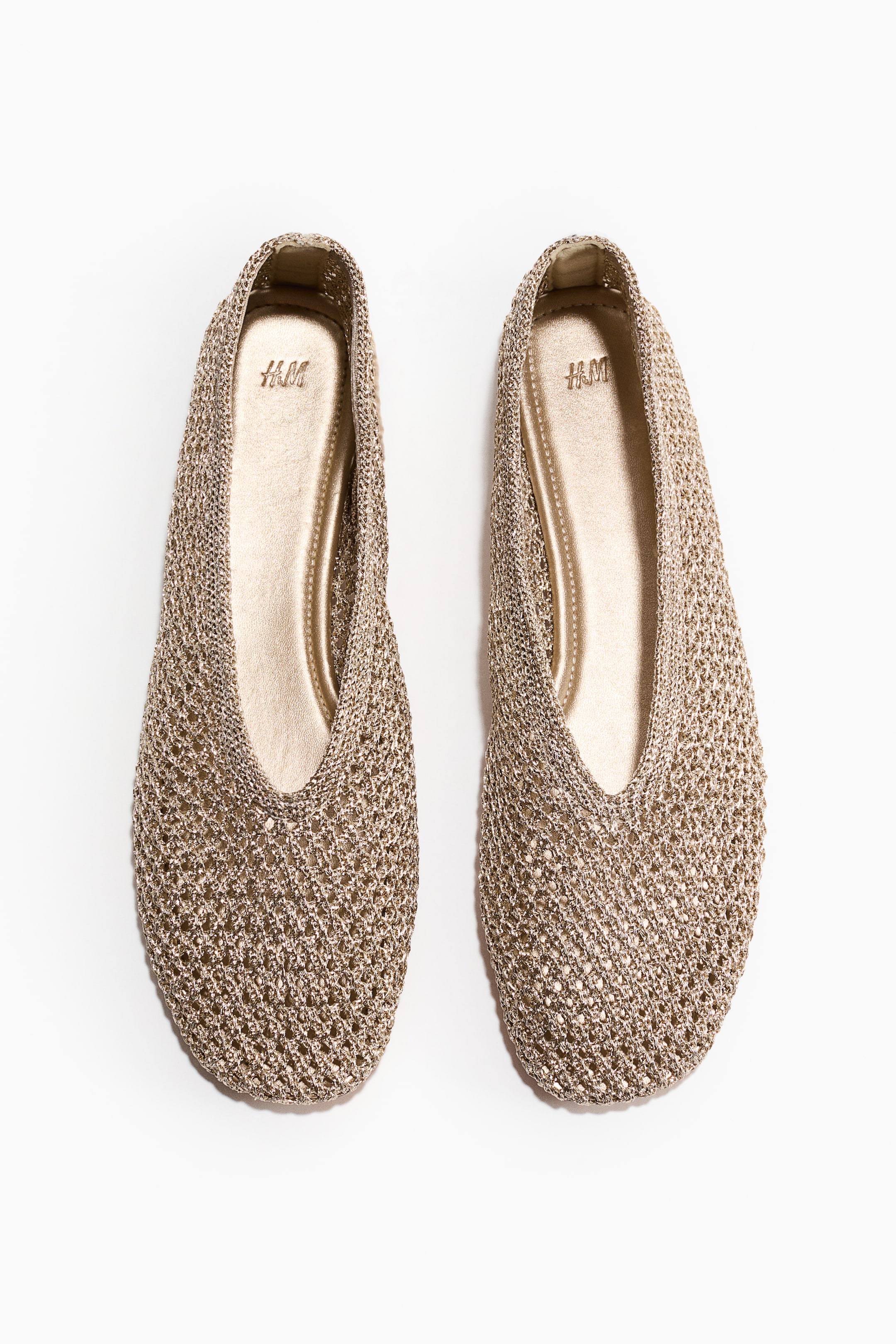 View larger image: A pair of gold ballet flats is presenting from the front, showcasing a knitted mesh upper with a rounded toe and a low-cut vamp. Each shoe is featuring a gold-toned insole with an H&M logo.