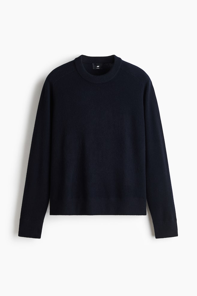 A navy blue crew-neck jumper is shown from the front, featuring a fine-knit fabric with a classic ribbed collar, ribbed cuffs, and a ribbed hem. - 1