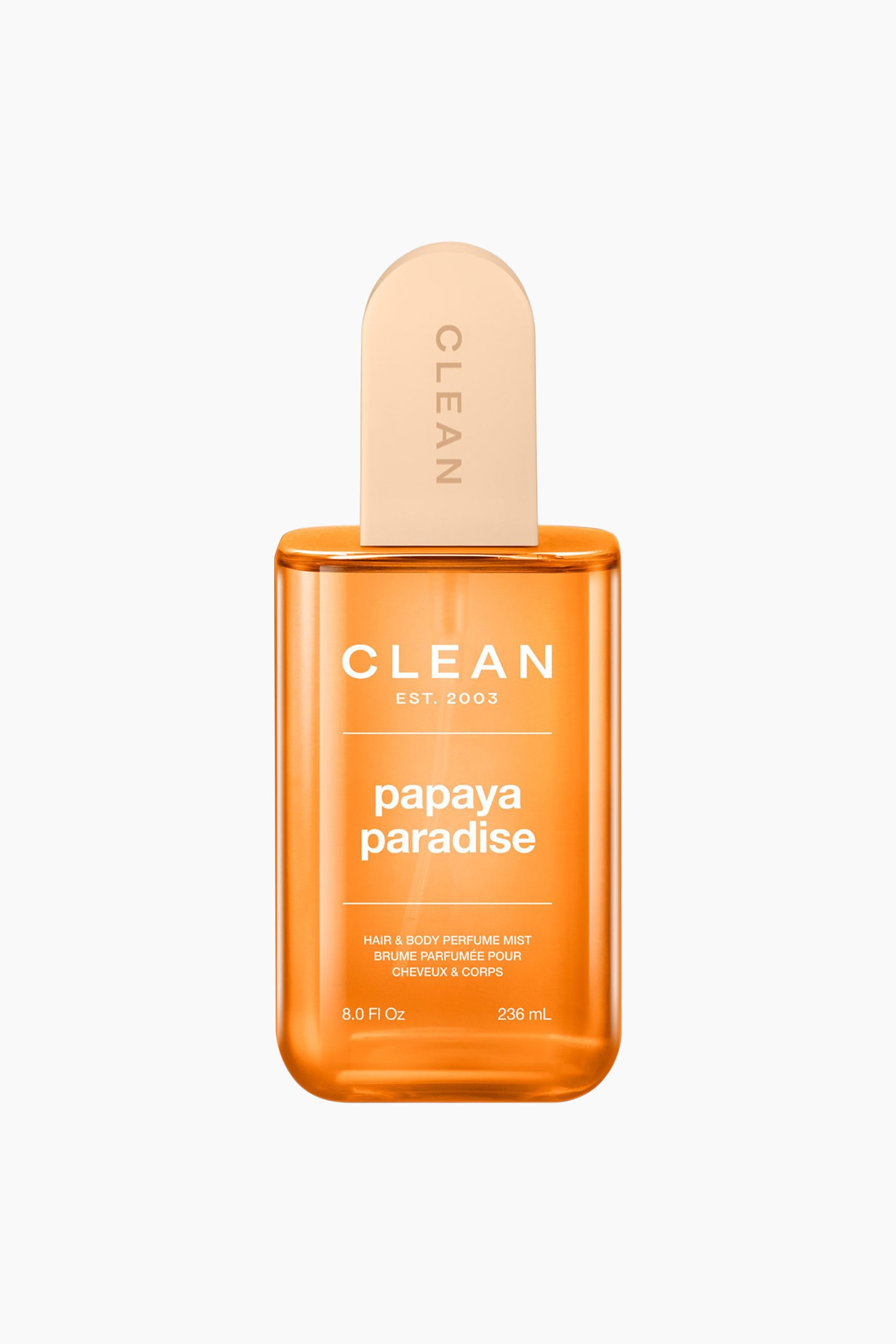 Se større billede: En gennemsigtig orange rektangulær flaske med Clean Papaya Paradise Hair & Body Perfume Mist står oprejst og har en lys beige rundet hætte med 'CLEAN' skrevet lodret. På forsiden er der en etiket, der viser 'CLEAN EST. 2003', 'papaya paradise', 'HAIR & BODY PERFUME MIST' samt volumenoplysninger '8.0 Fl Oz 236 mL'.