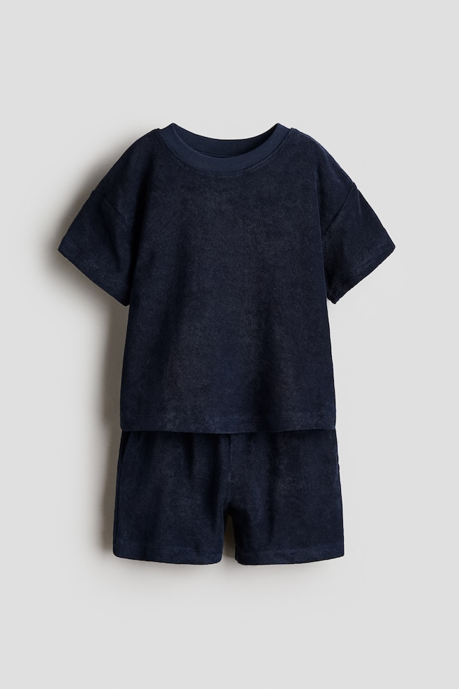 A navy soft terry T-shirt and shorts set is showcasing its front design. The T-shirt is featuring a ribbed neckline and dropped shoulders, and the shorts are designed with an elasticated waist. - 1